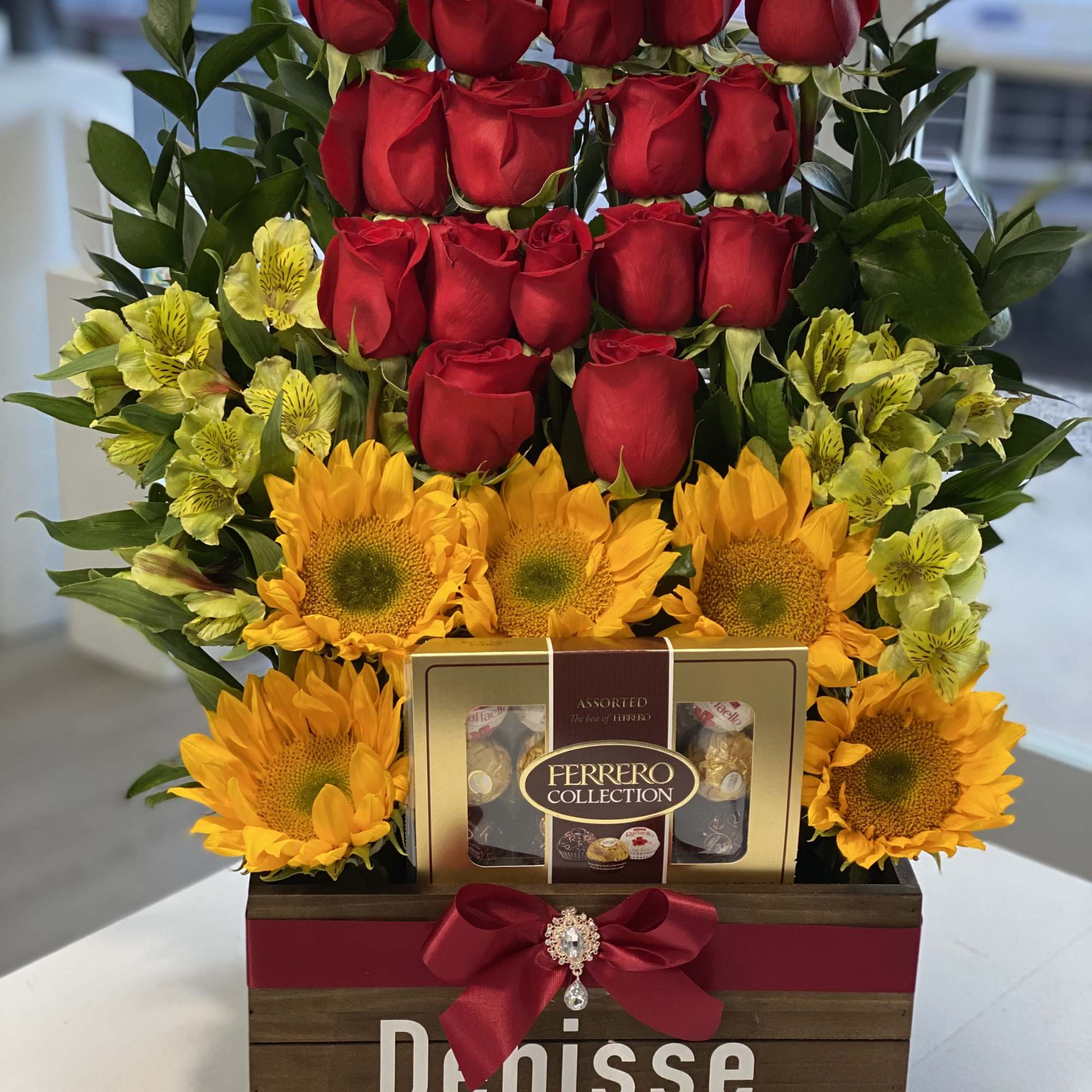 Red roses and sunflowers arranged with chocolates in a wooden gift box