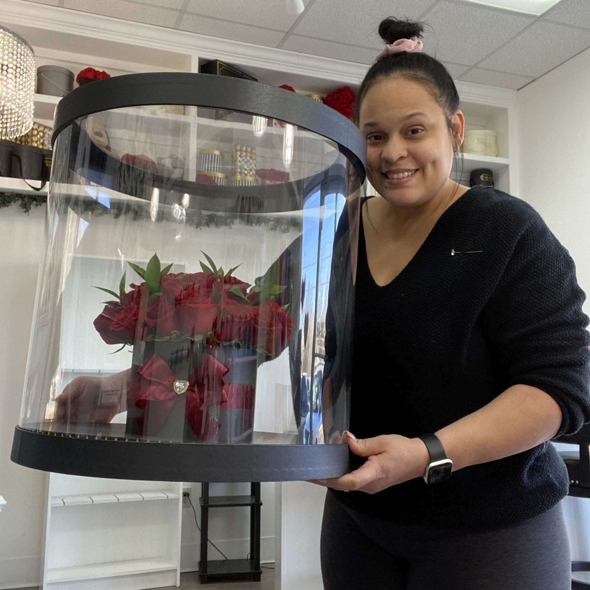 Woman holding a large clear display case with red roses inside
