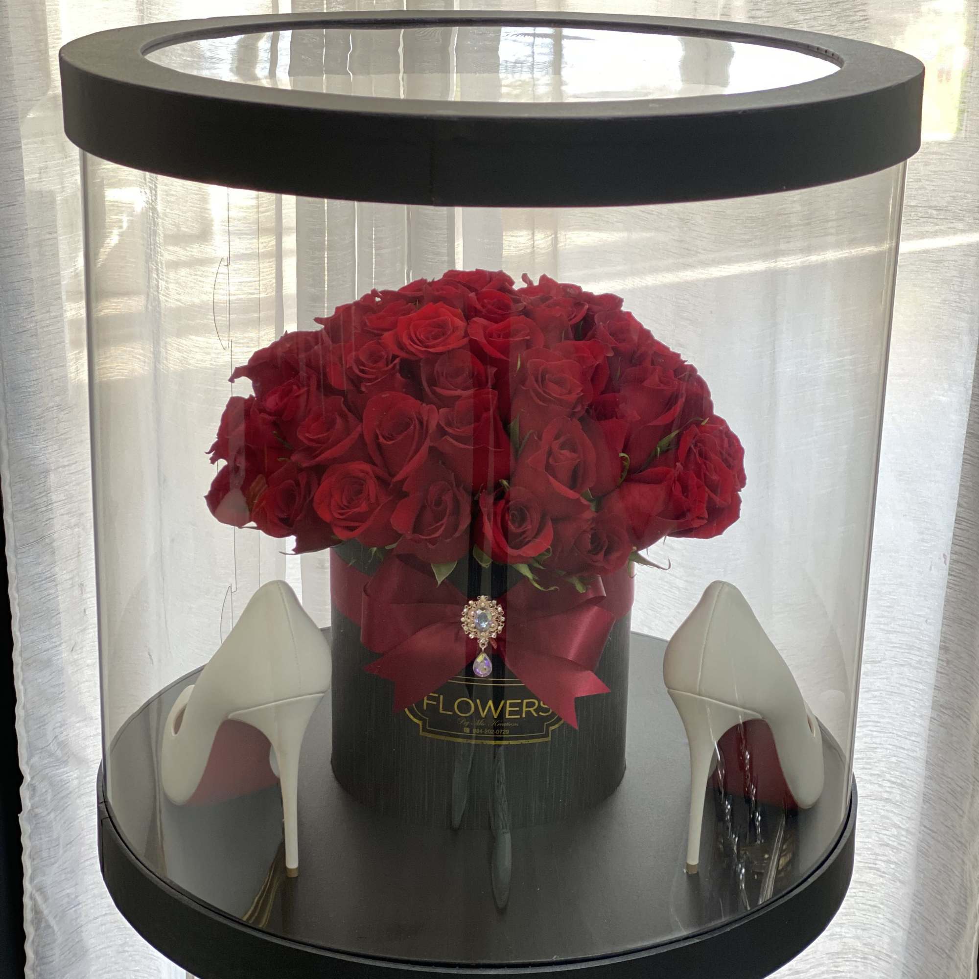 Red roses in a black hatbox with white high heels