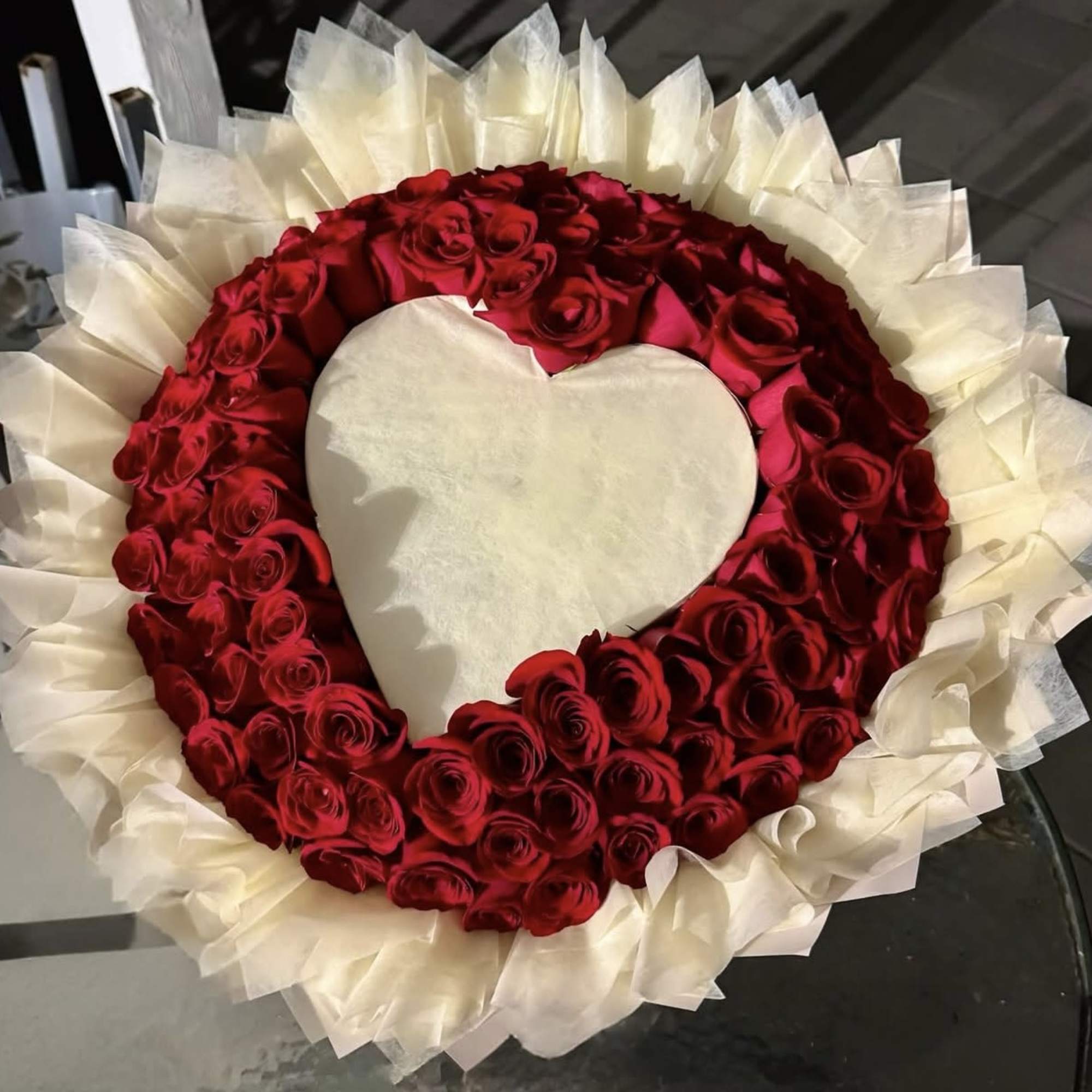 Heart-shaped arrangement of red roses with white wrapping around it