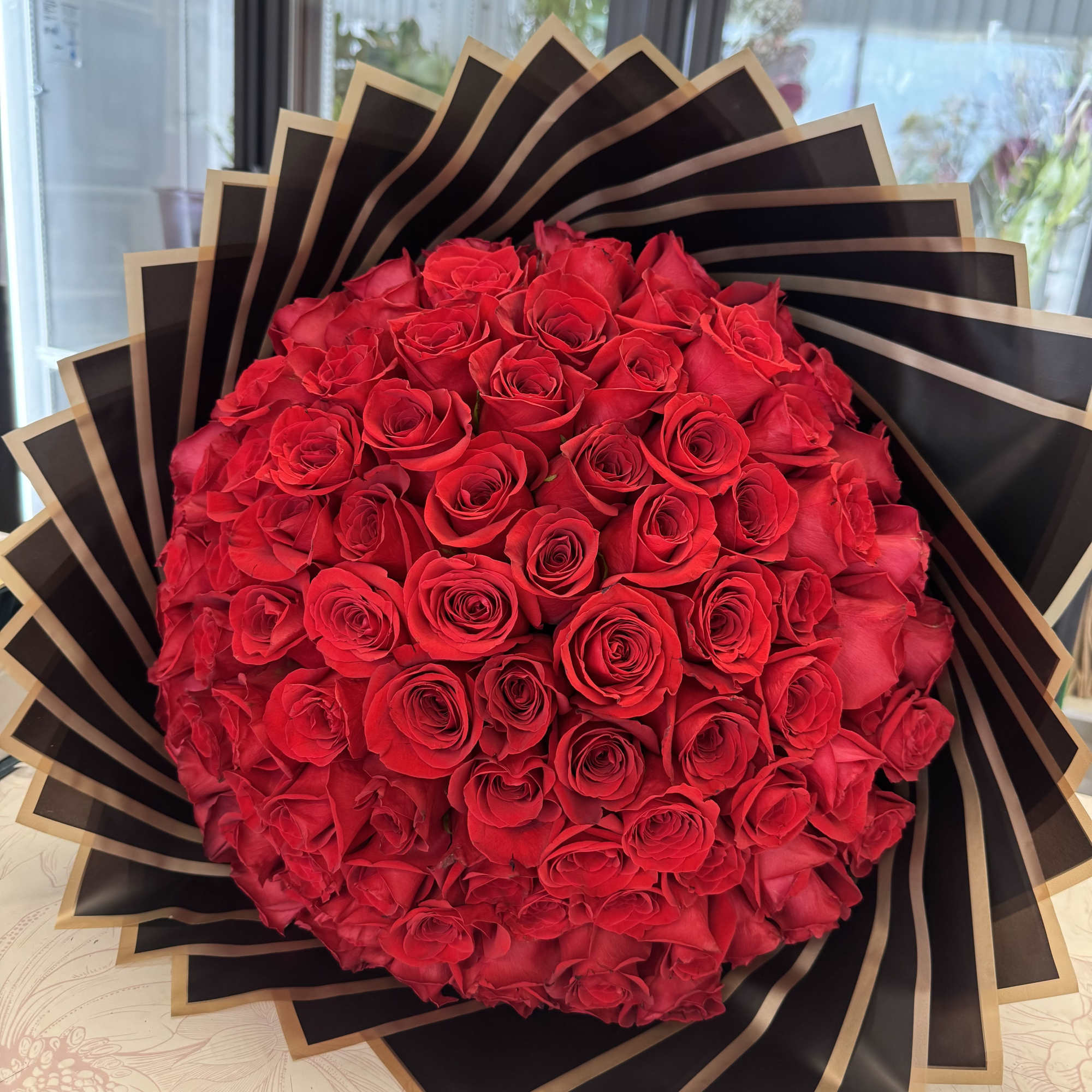 Large bouquet of red roses wrapped in black and gold paper