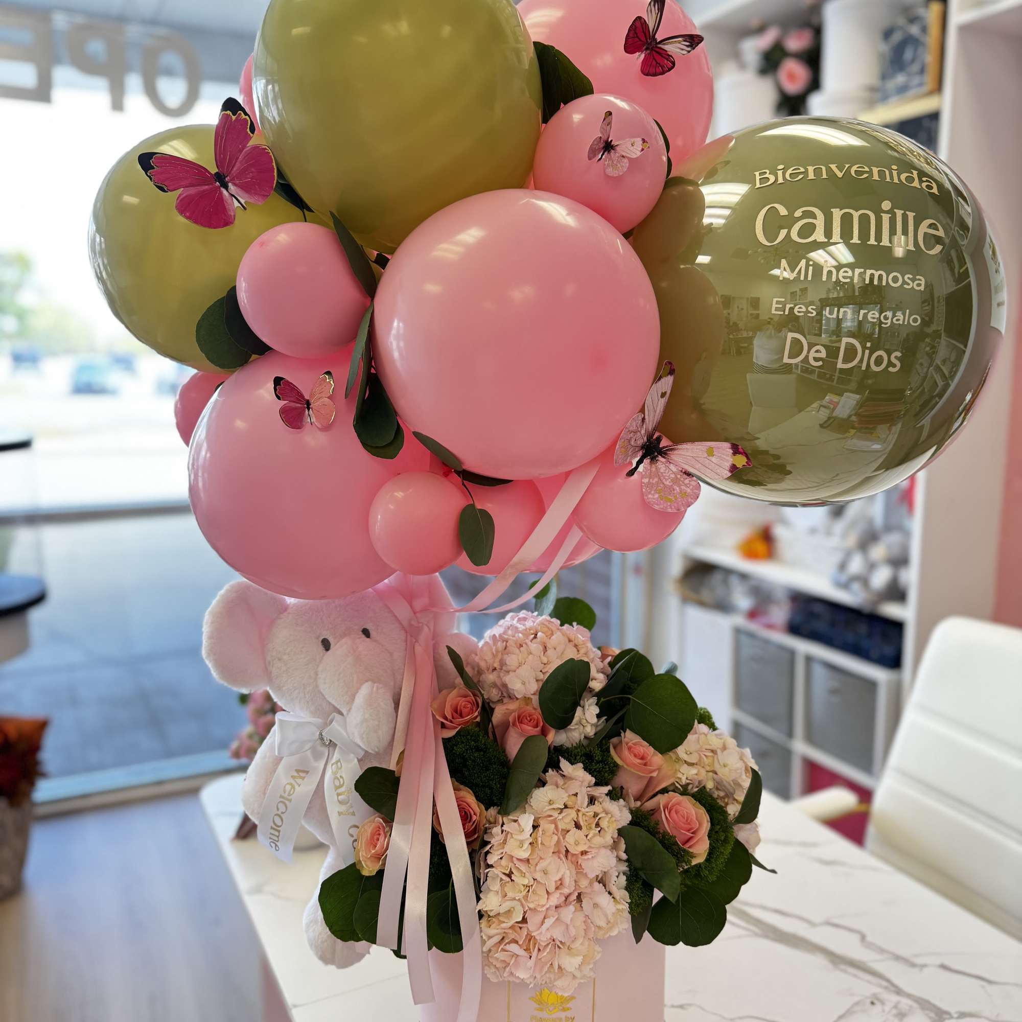 Pink and gold balloon arrangement with a teddy bear and flowers in a pink box