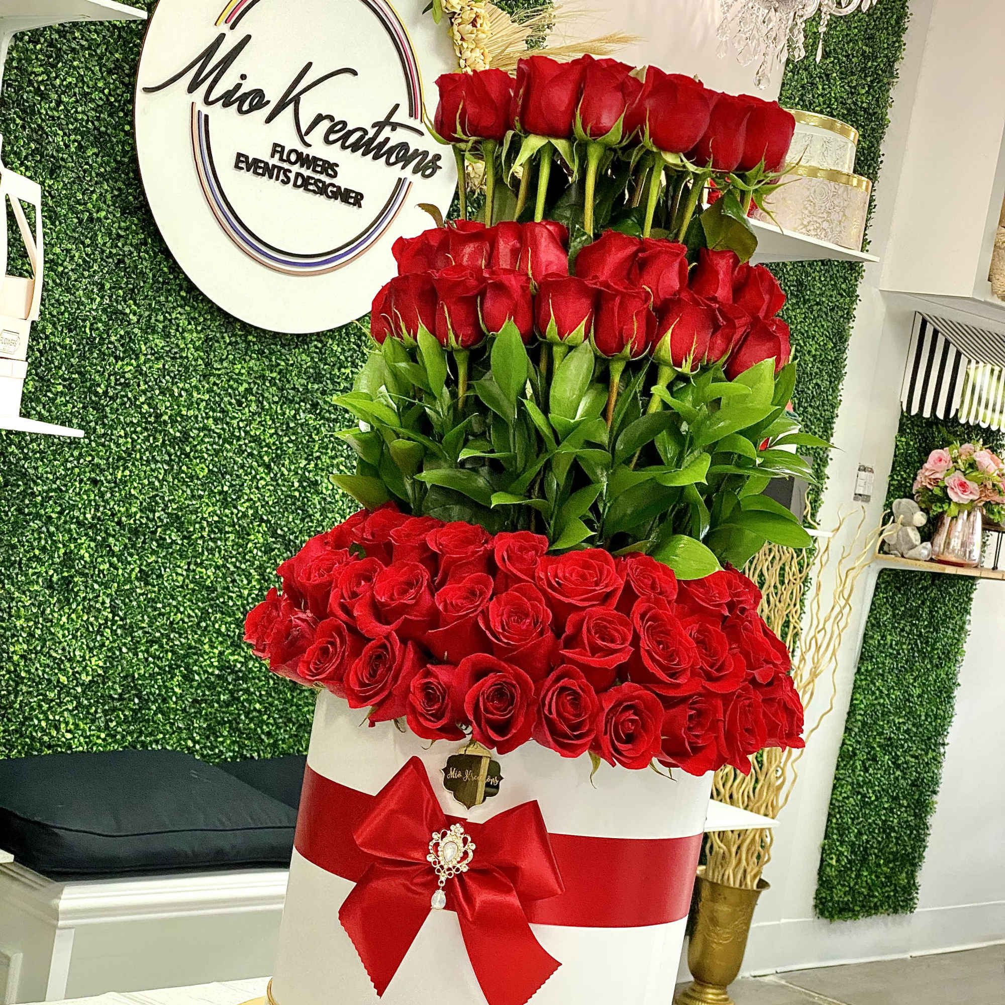 Tall tiered arrangement of red roses in a white box with a red bow