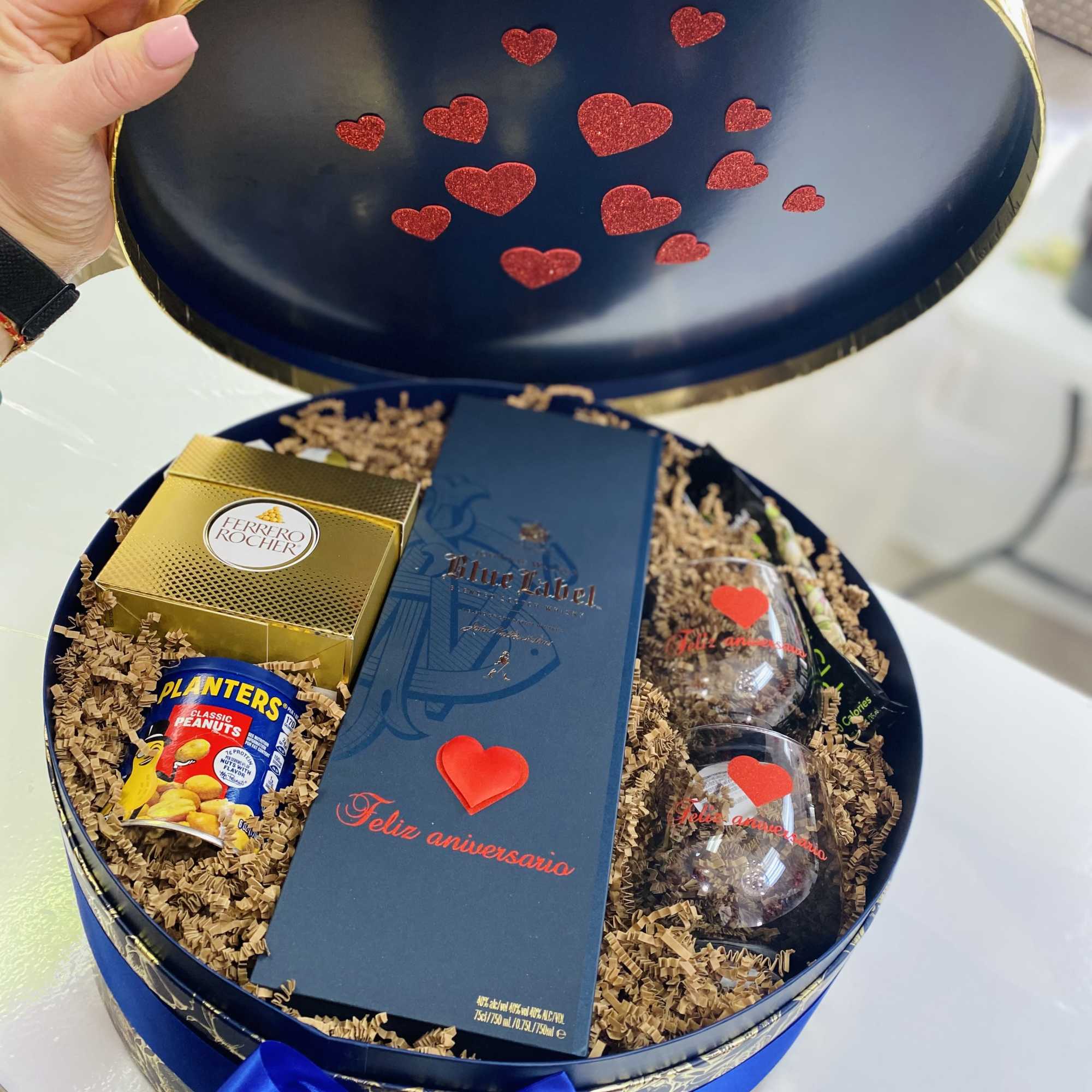 Gift box with chocolates, peanuts, and two glasses inside a round blue case