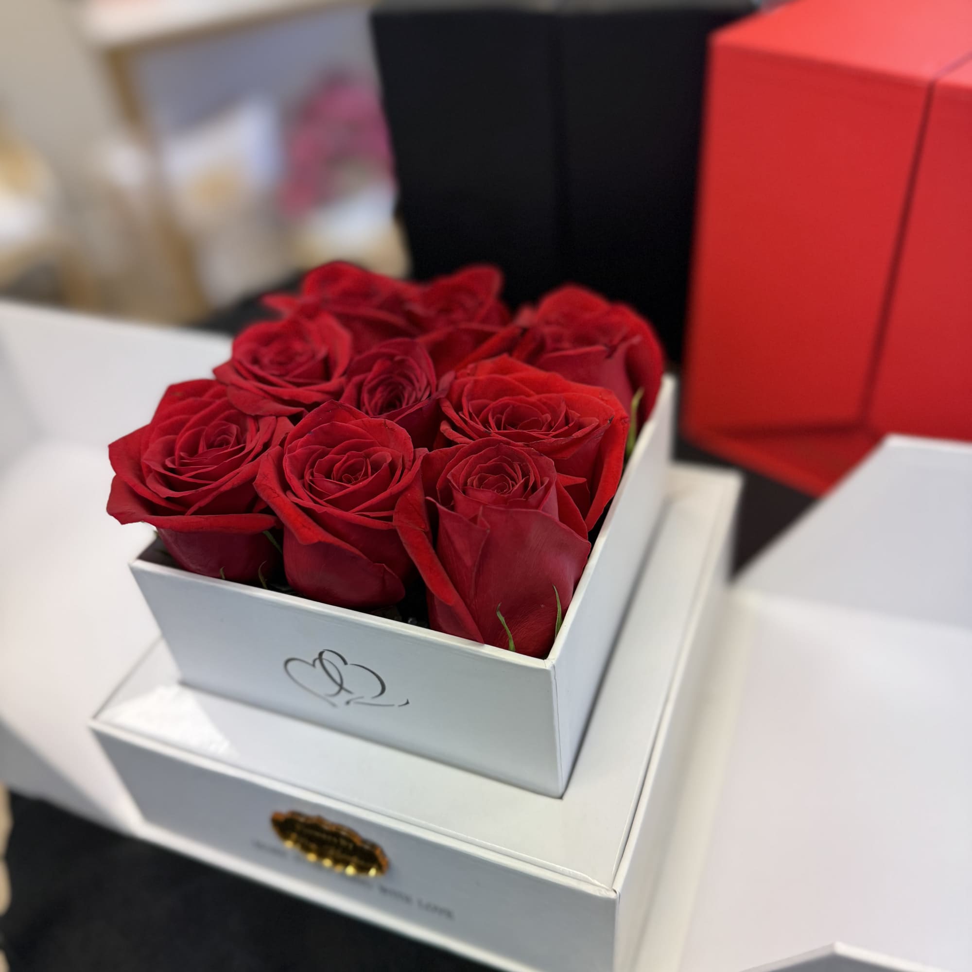 Red roses arranged in a white gift box on stacked boxes