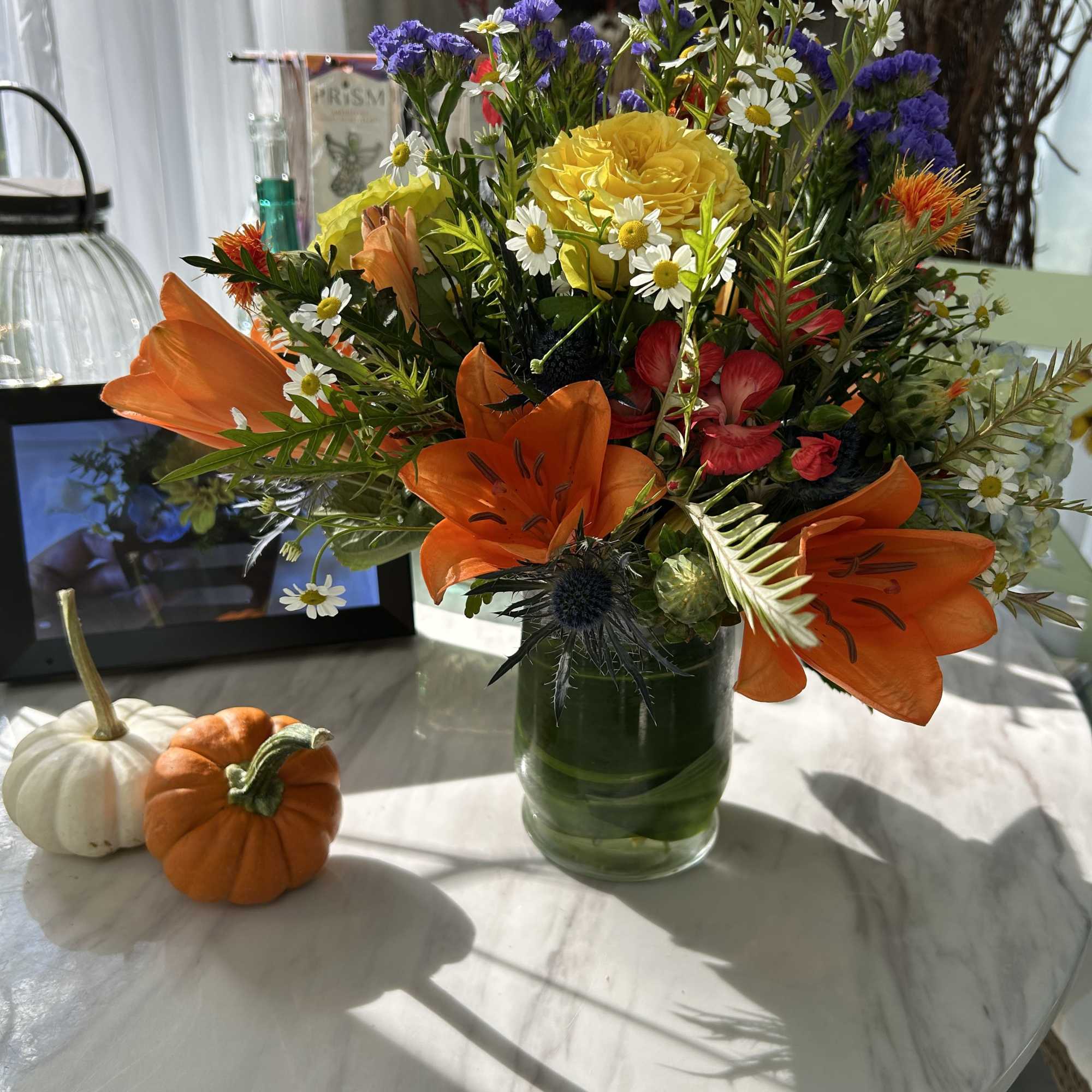 Mixed bouquet with orange lilies and yellow roses in a glass vase