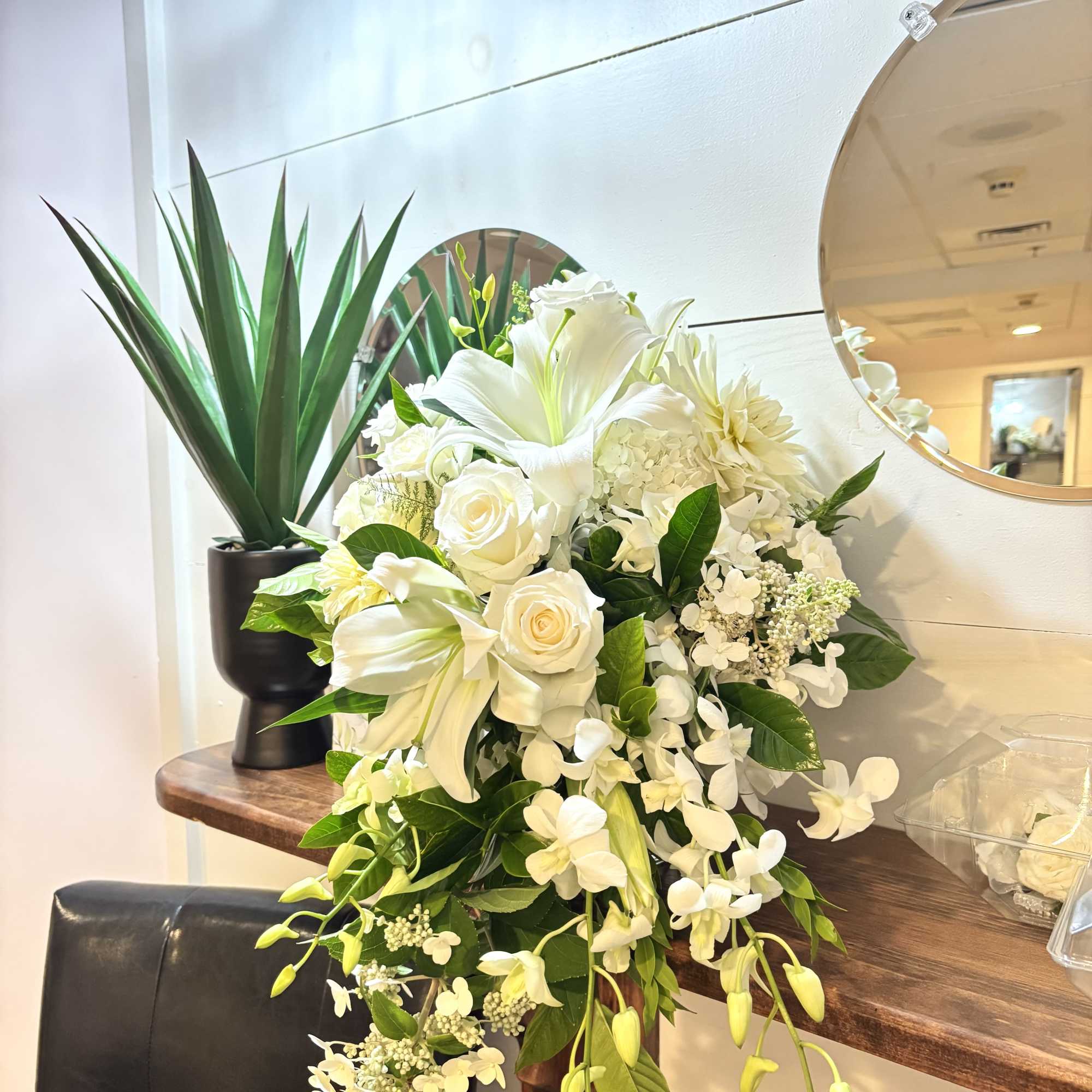 White floral arrangement with roses and lilies in a cascading design