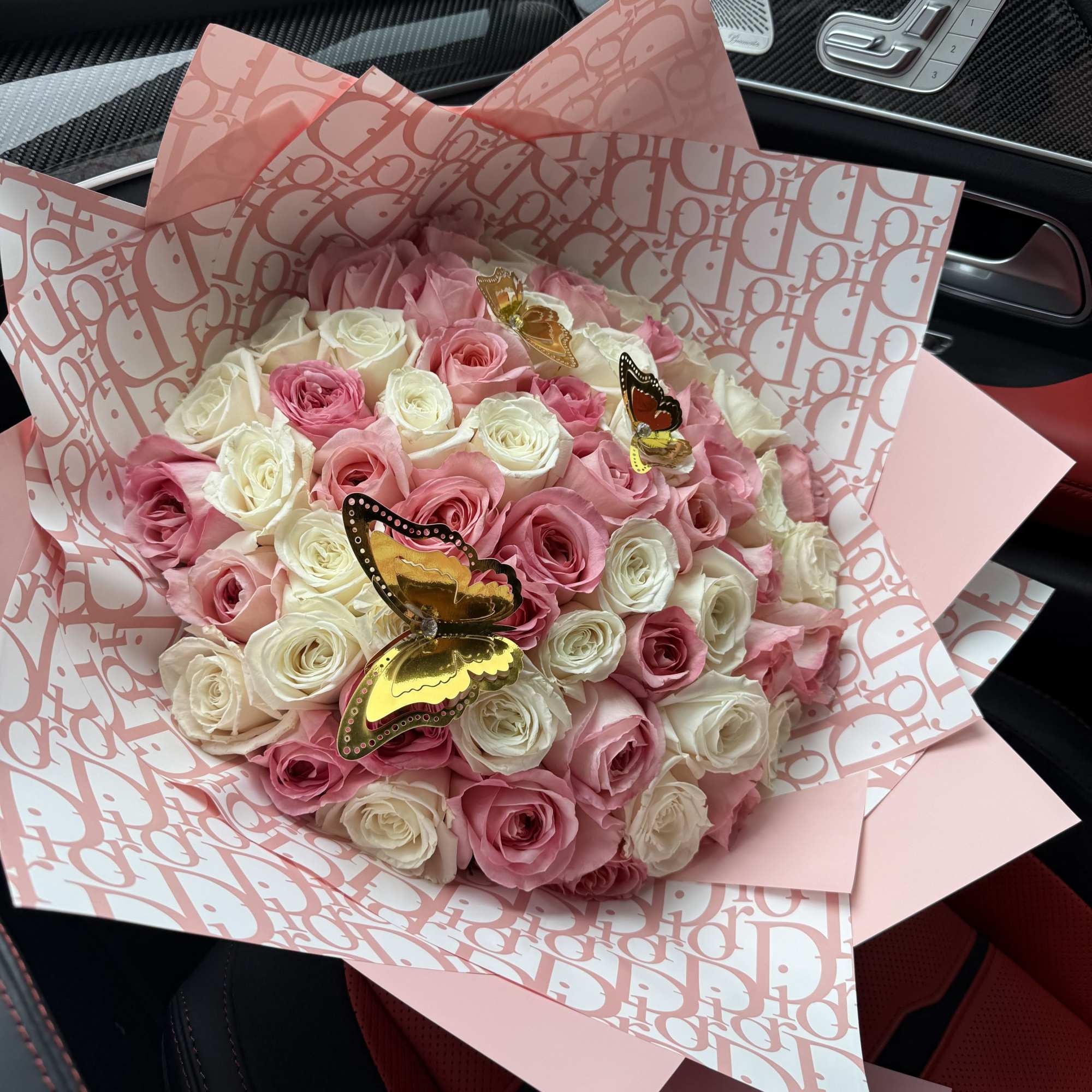 Pink and white rose bouquet wrapped in patterned pink paper with butterfly picks