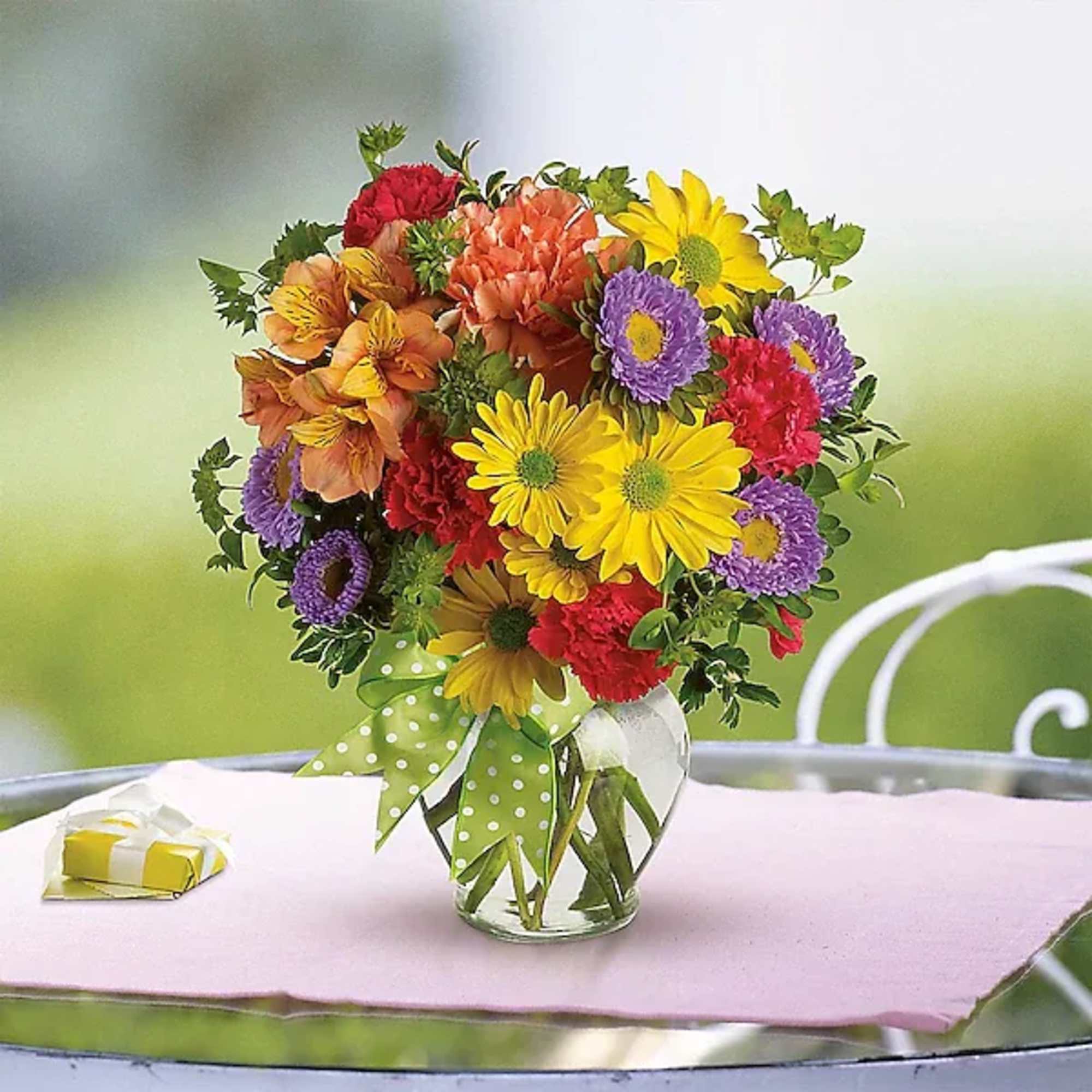 Colorful mixed bouquet in a clear glass vase with a polka-dot ribbon