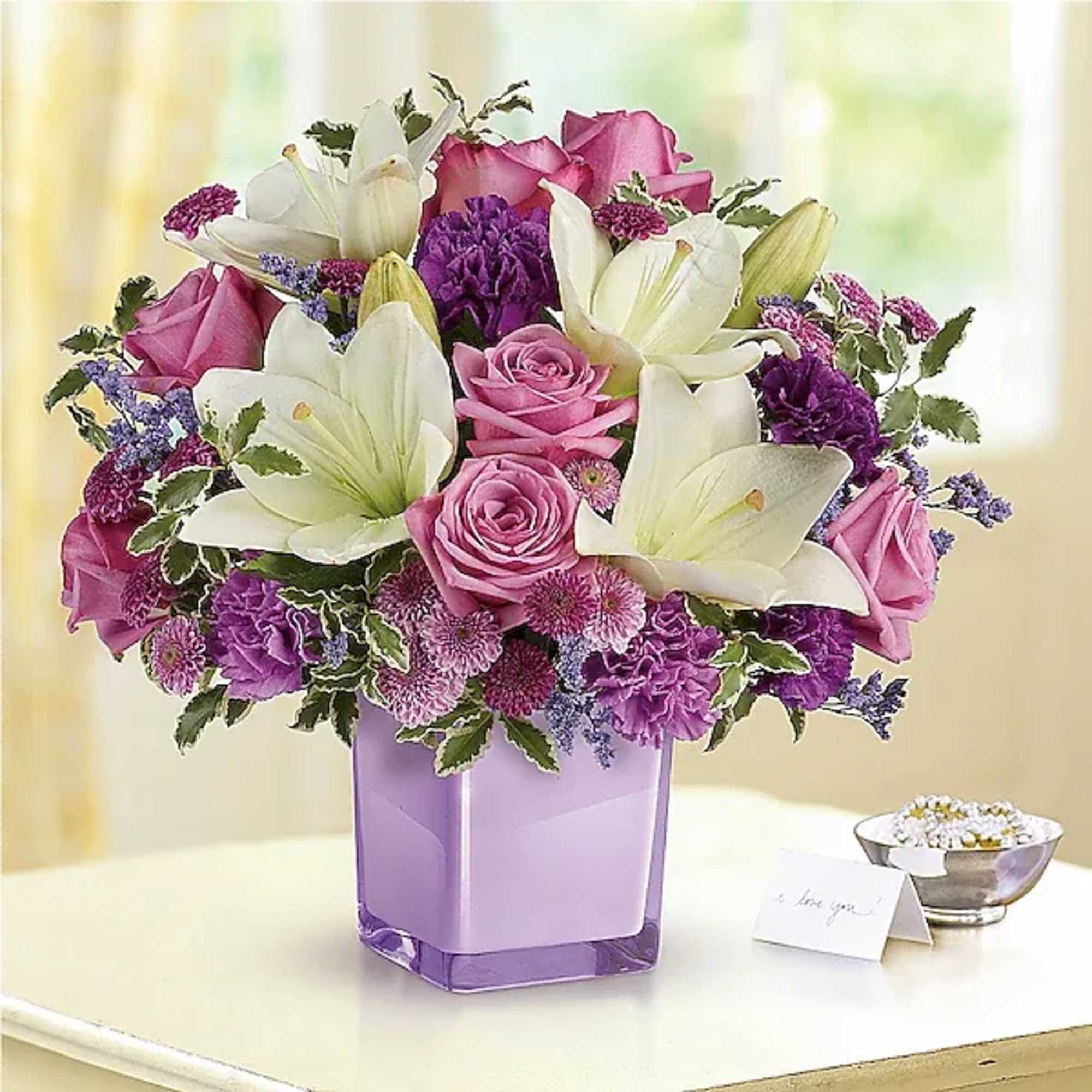 Pink roses and white lilies arranged in a purple vase