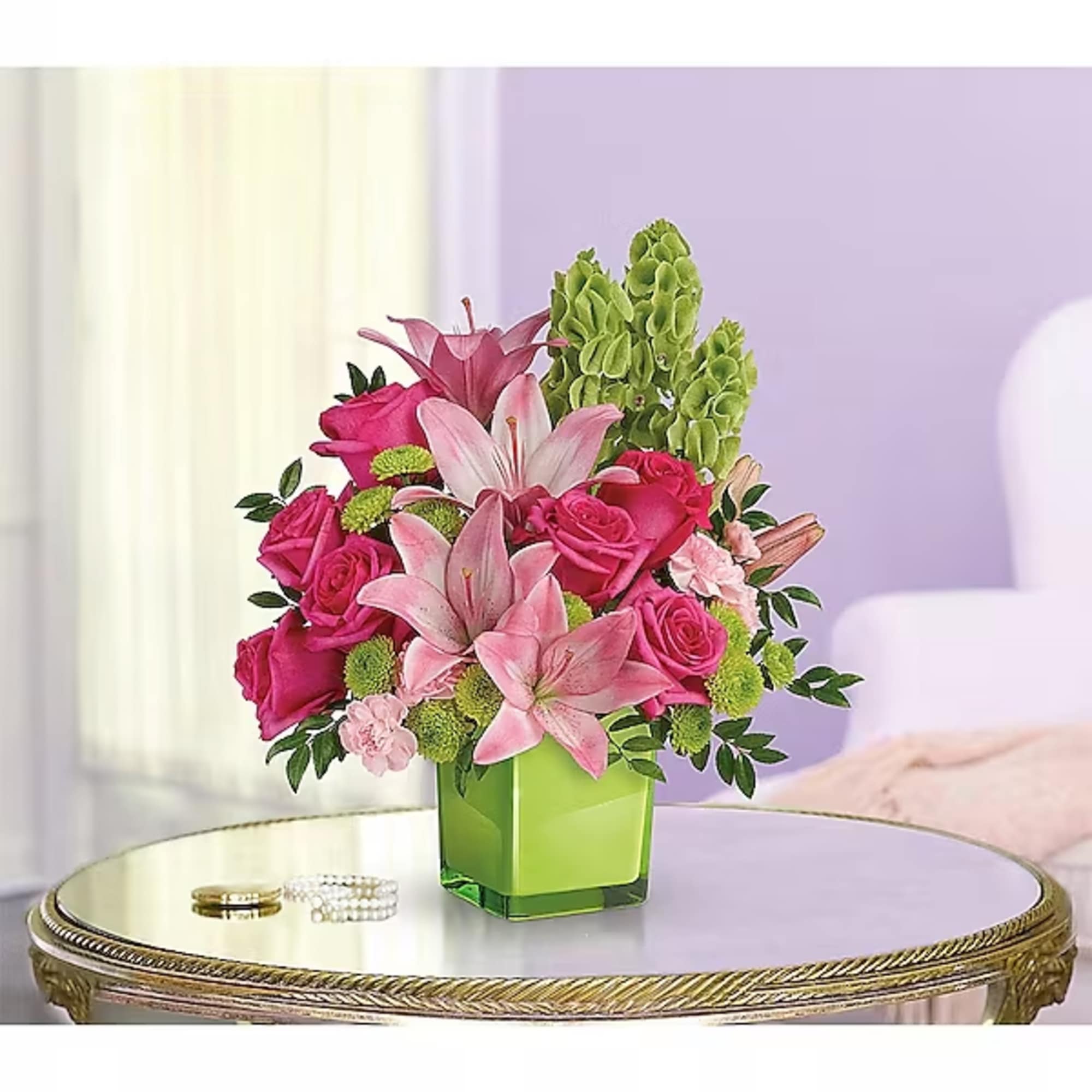 Pink roses and lilies arranged in a green square vase