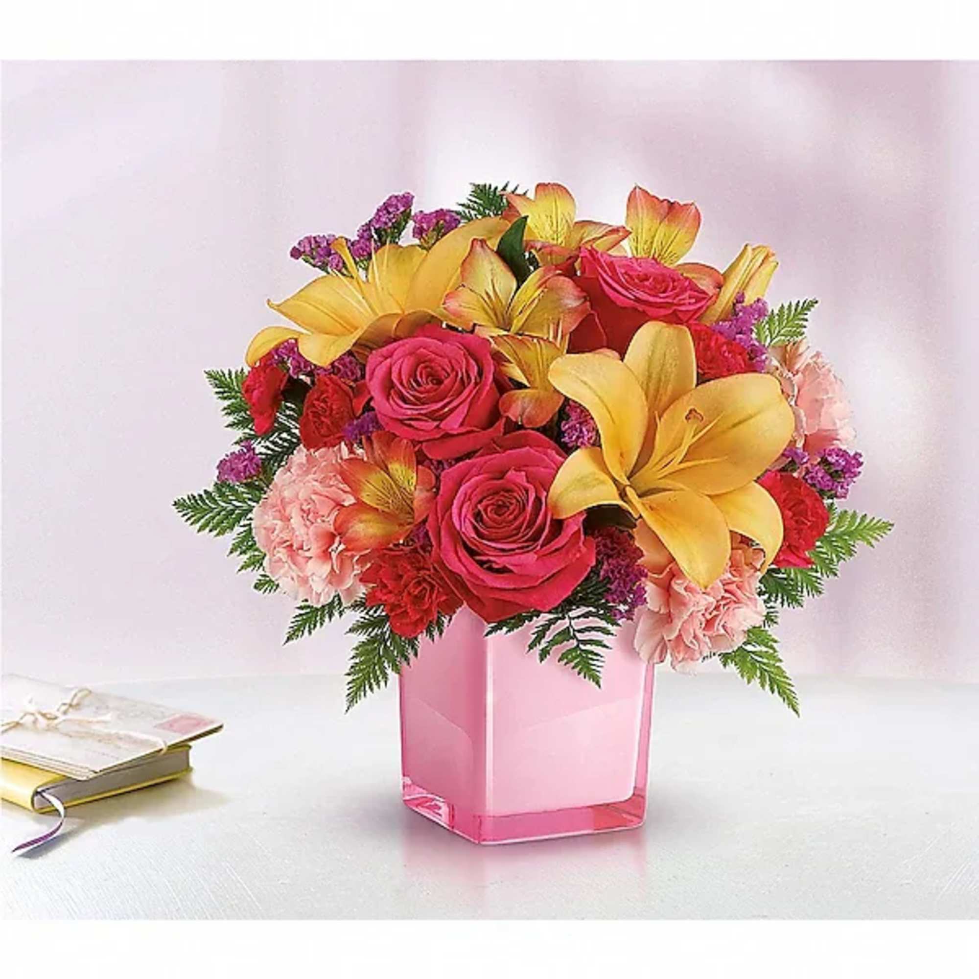 Pink and yellow floral arrangement in a pink glass vase