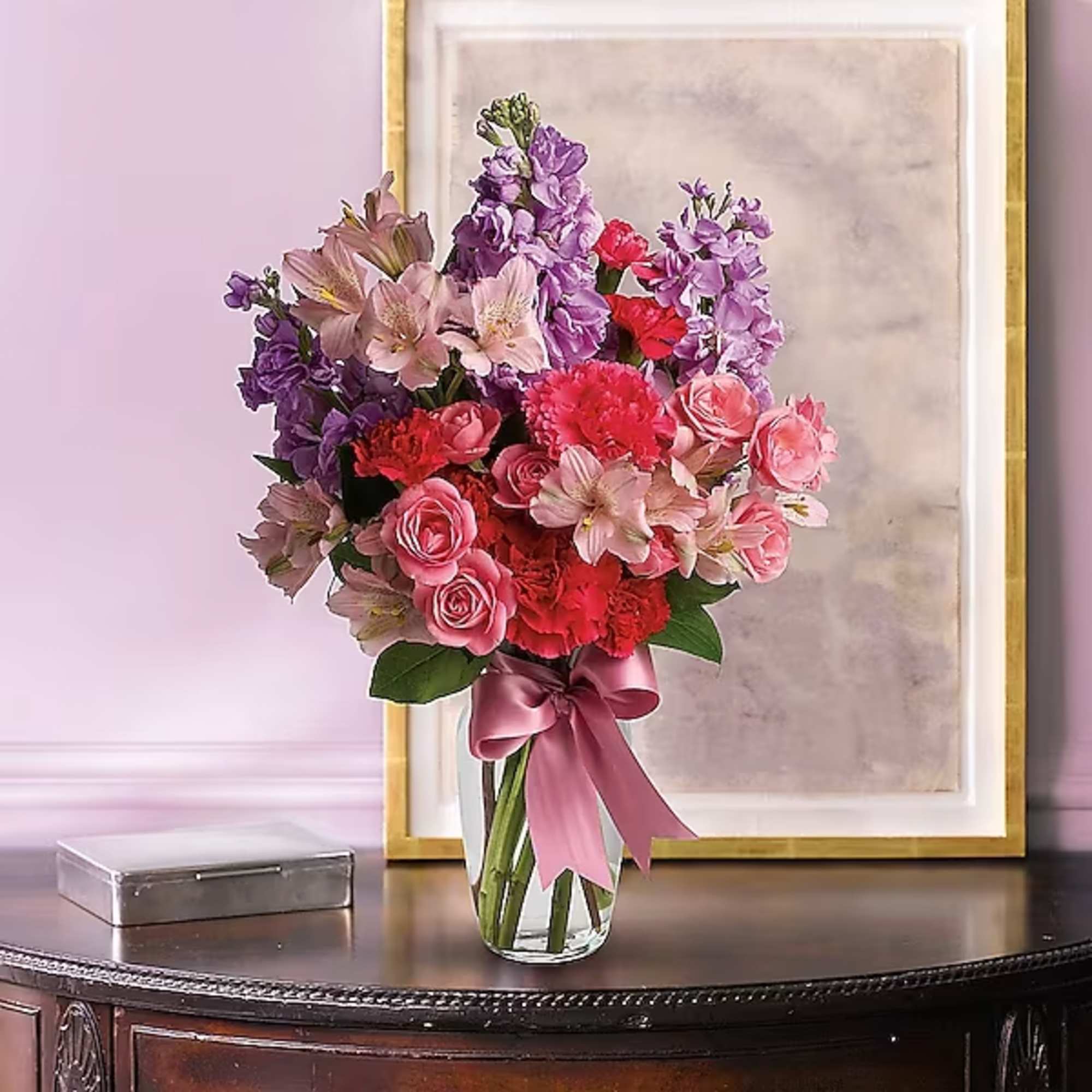 Pink and purple mixed bouquet in a clear glass vase with a ribbon
