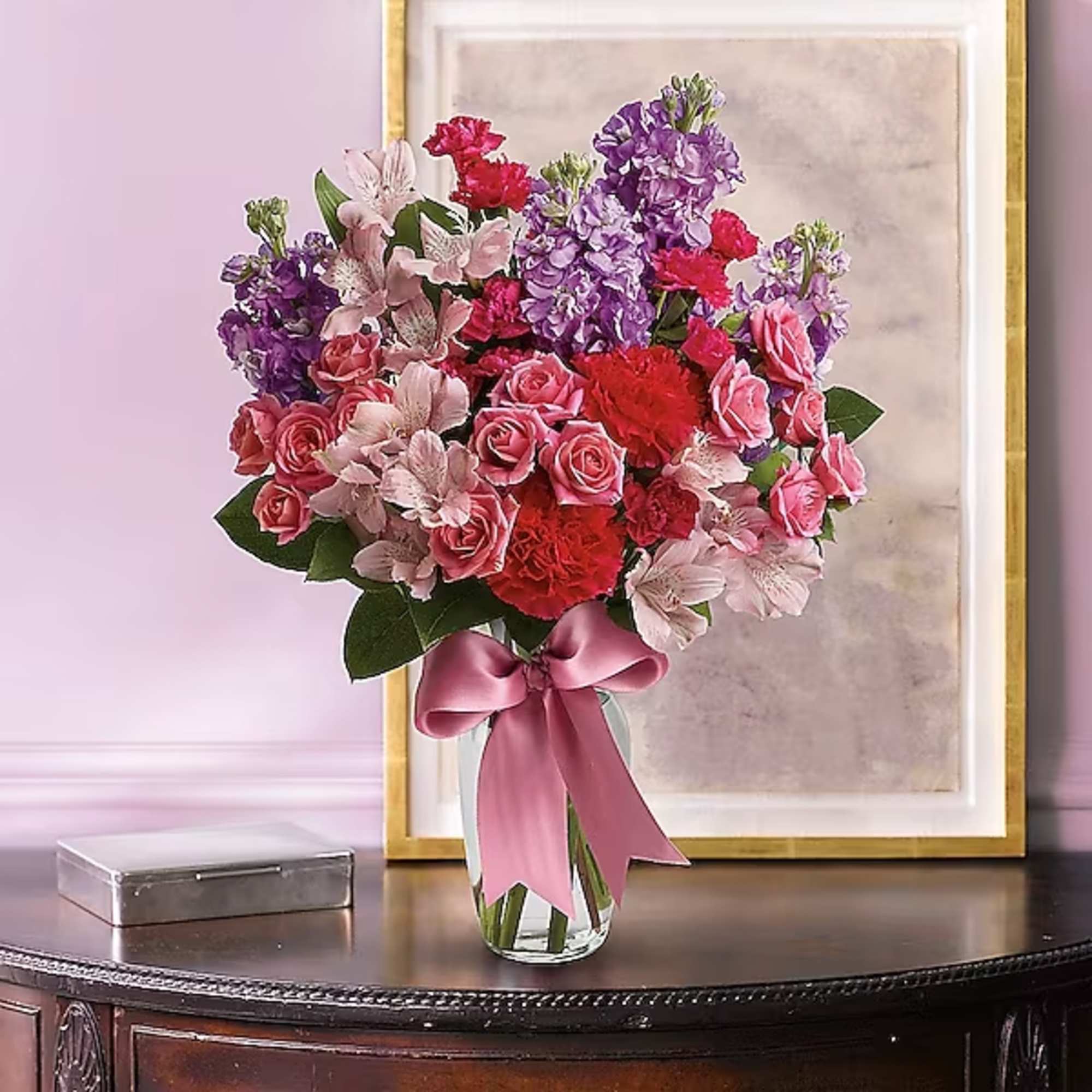 Bouquet of pink and purple flowers in a glass vase with a satin ribbon