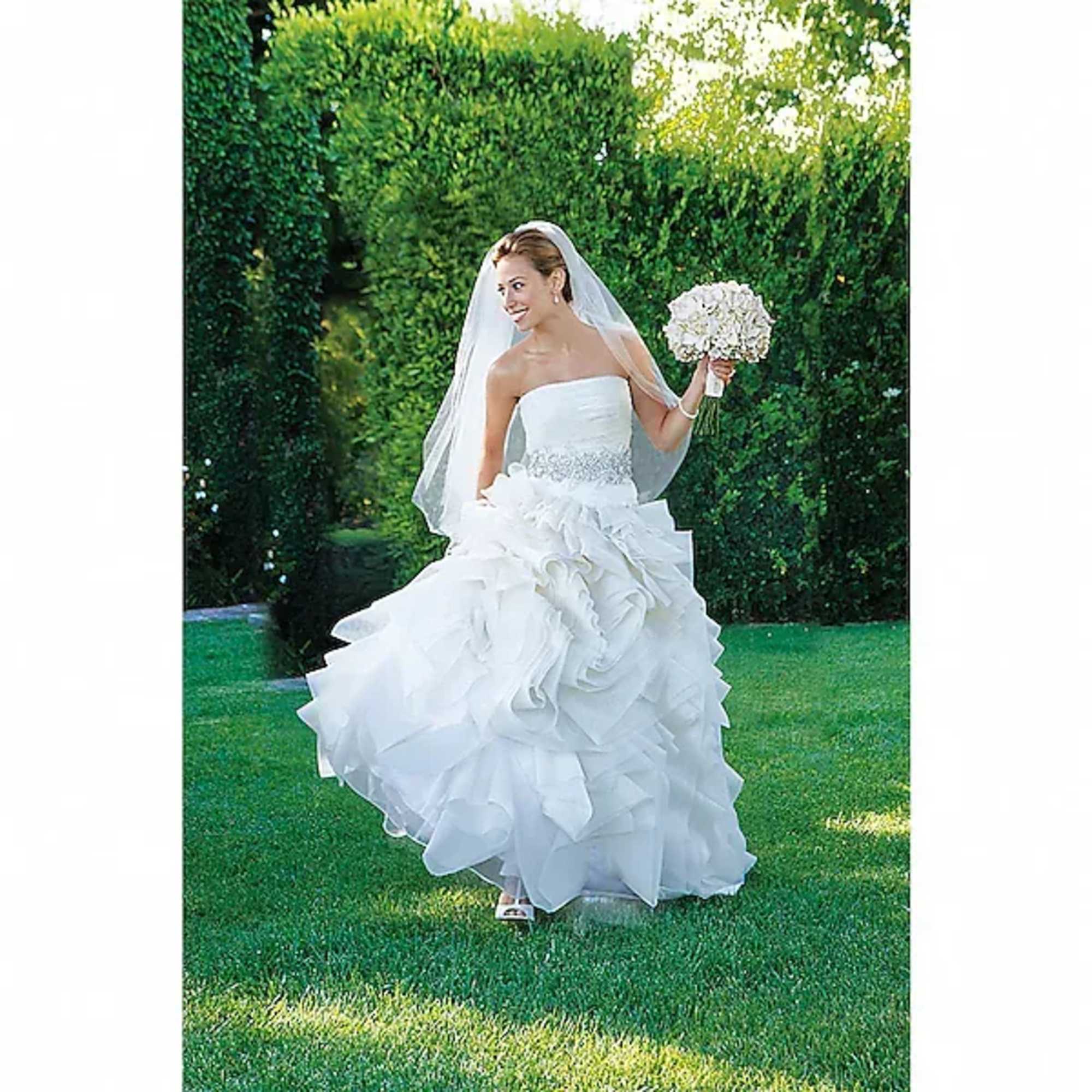 Bride in a white gown holding a white bouquet outdoors