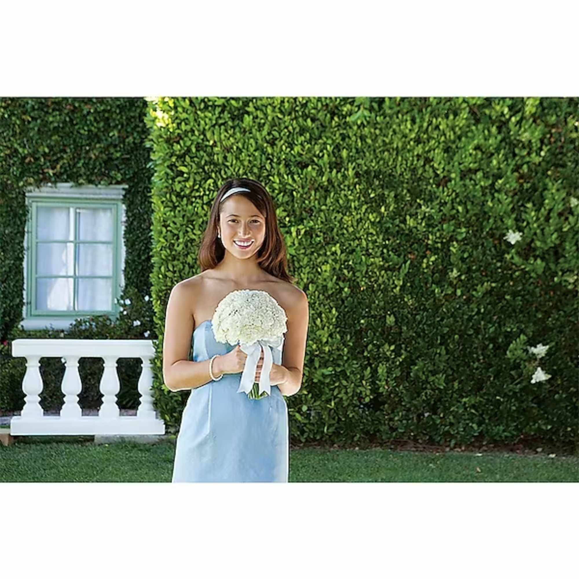 Woman in a blue dress holding a white bouquet outdoors