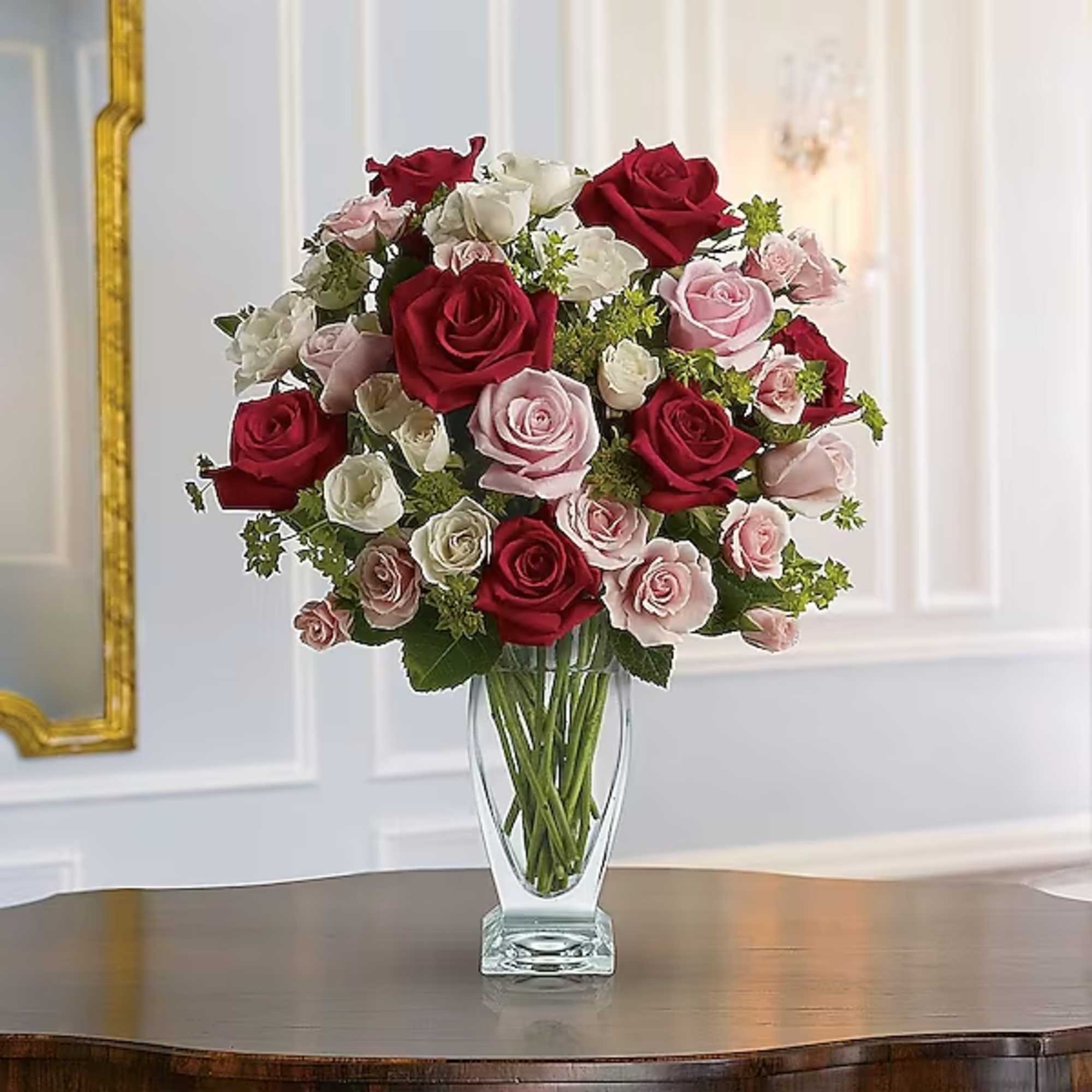 Bouquet of red, pink, and white roses in a clear glass vase