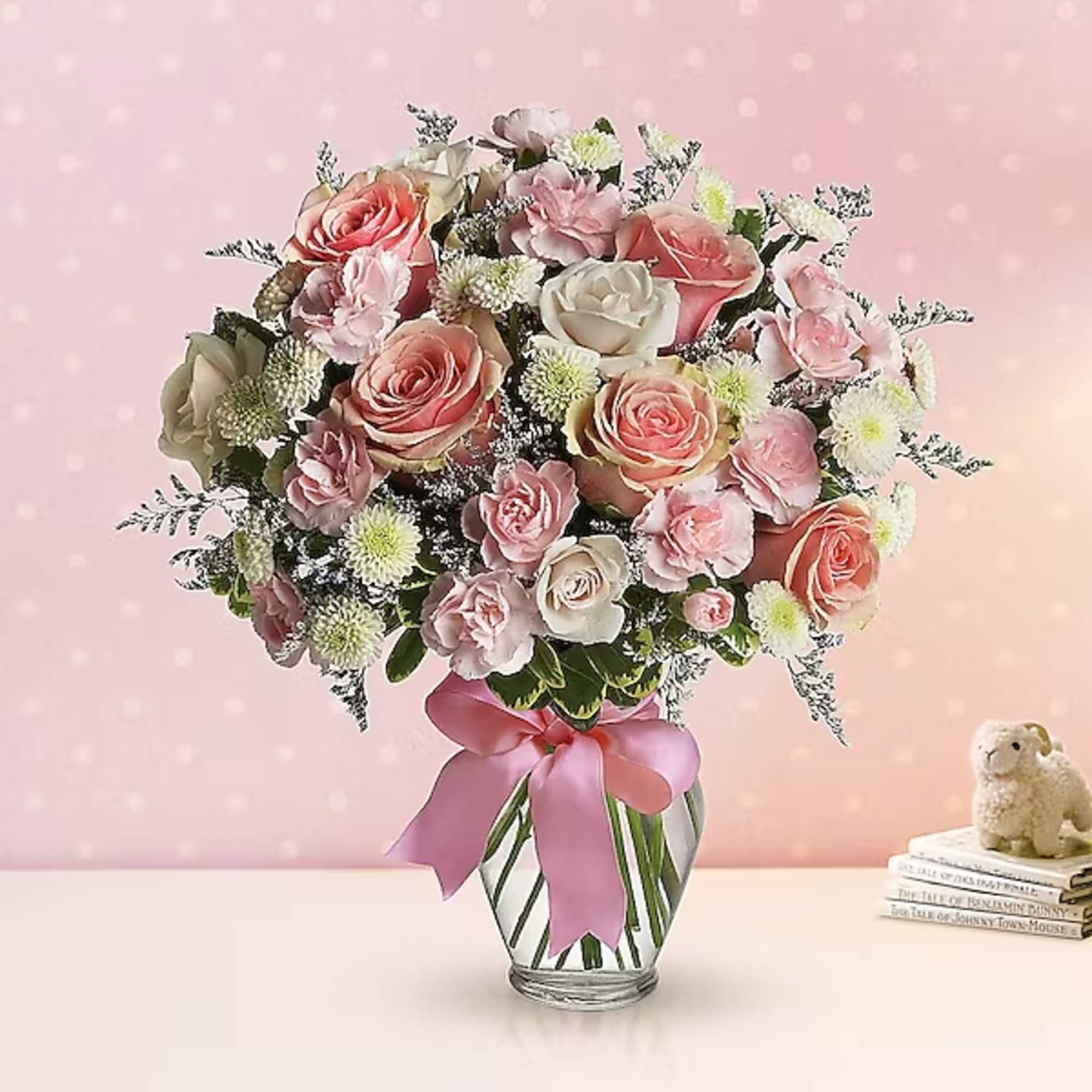 Pink and white rose bouquet in a glass vase with a satin ribbon