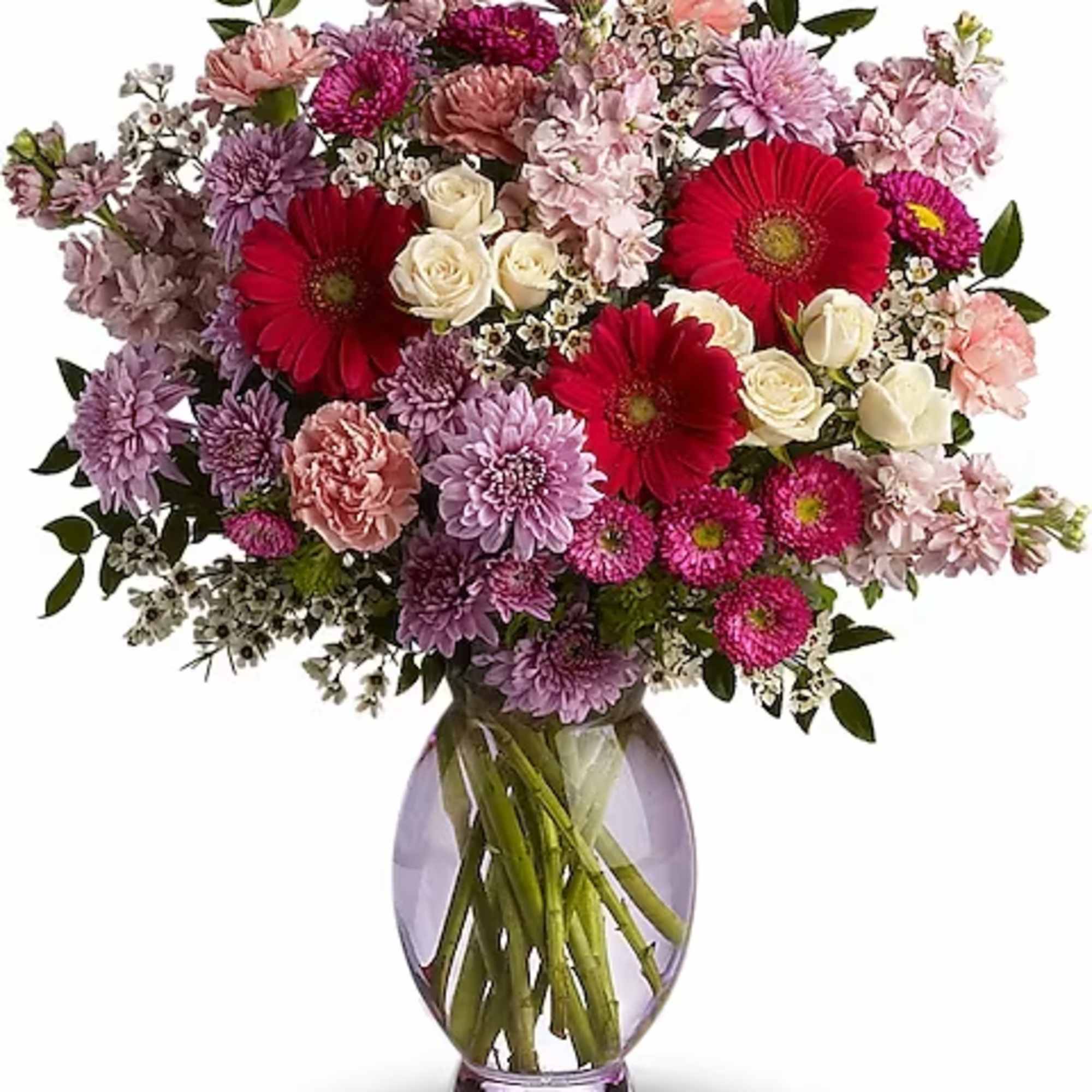 Mixed pink, purple, and red flowers in a glass vase