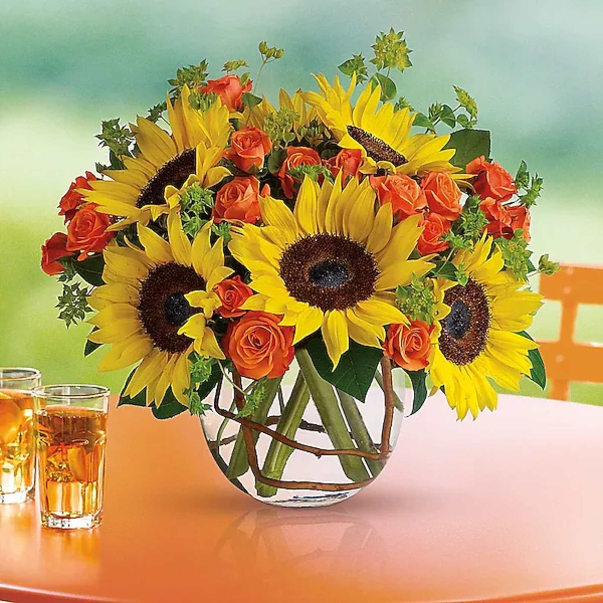 Bouquet of sunflowers and orange roses in a clear glass vase