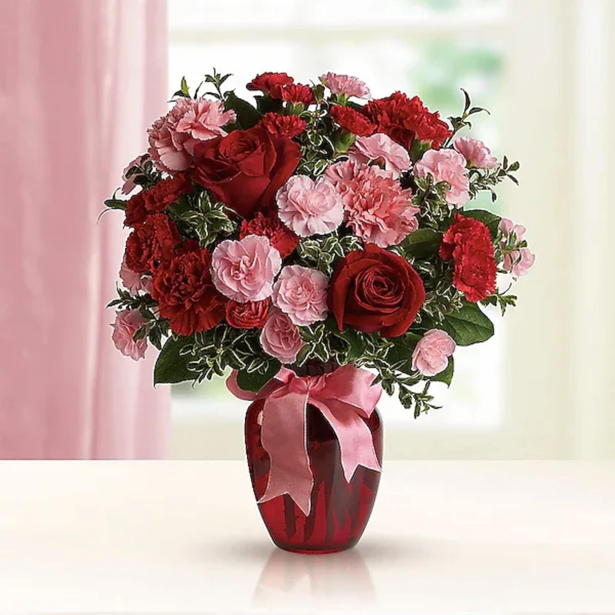 Red roses and pink carnations in a red vase with a pink ribbon, photo 2 of 2