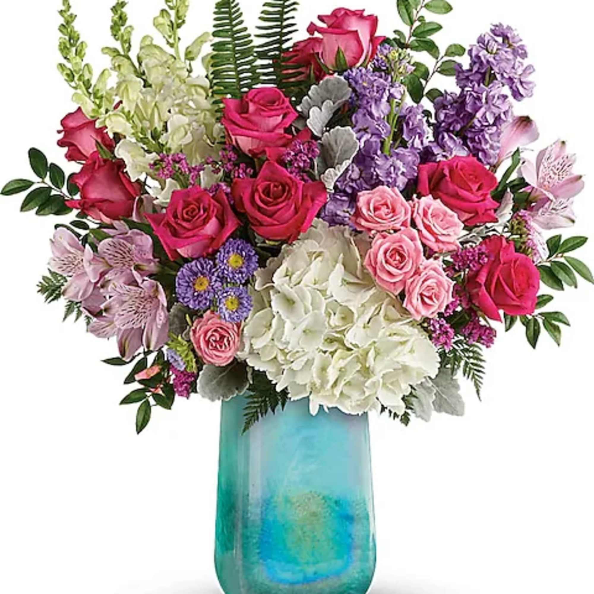 Mixed pink, purple, and white flowers in a turquoise glass vase