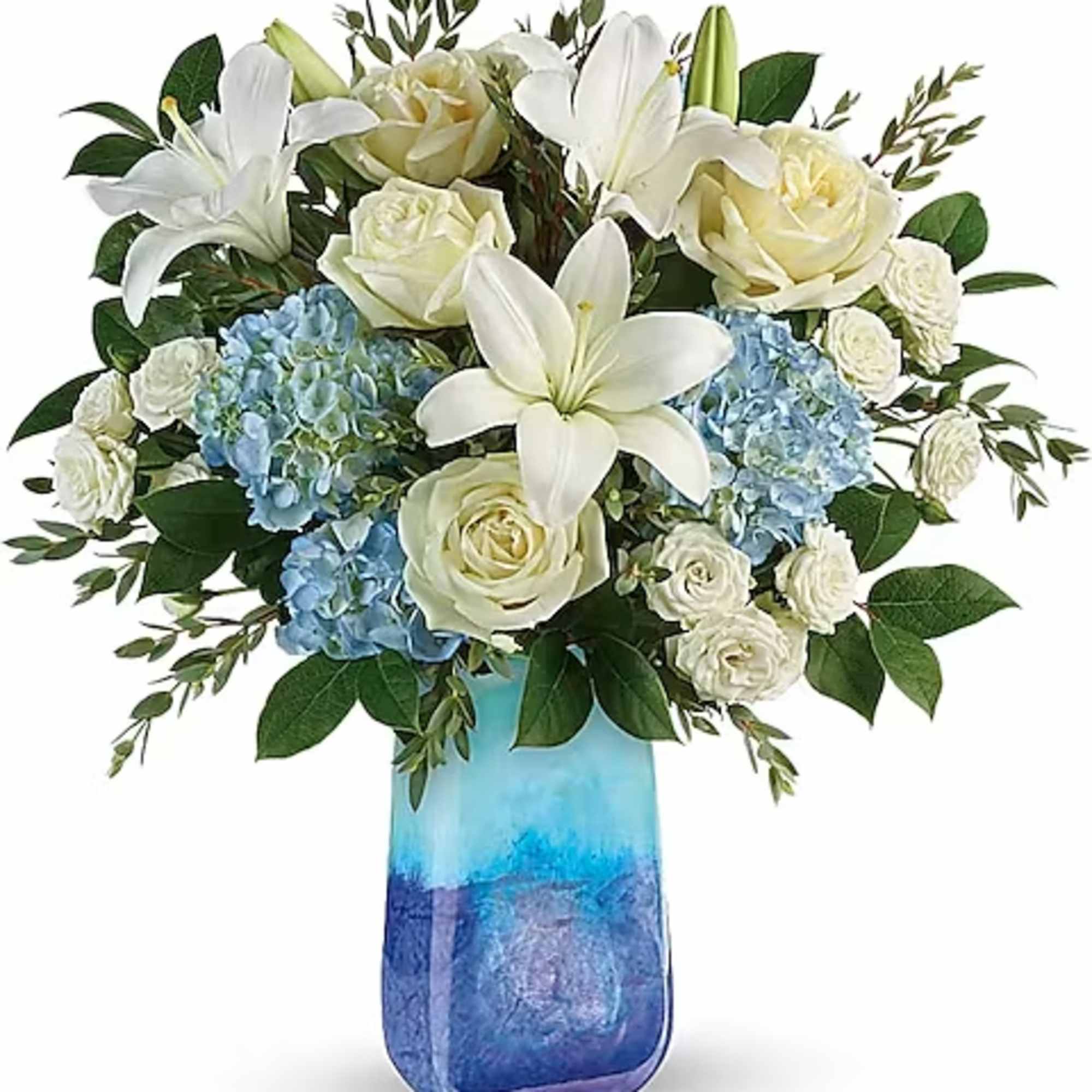 White lilies, roses, and blue hydrangeas in a blue glass vase