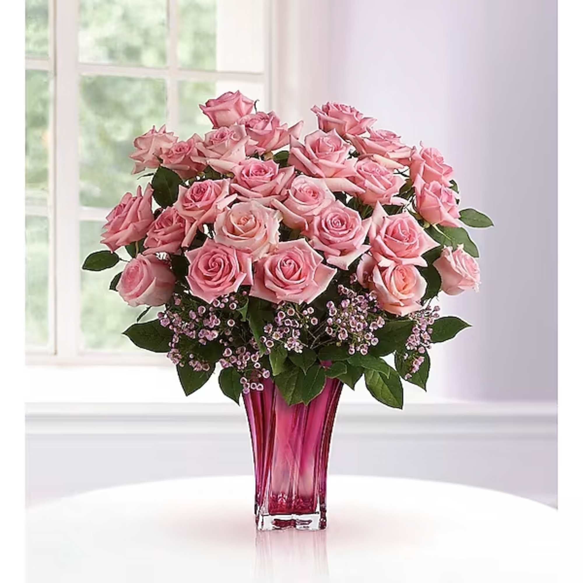 Pink roses arranged in a tall magenta glass vase