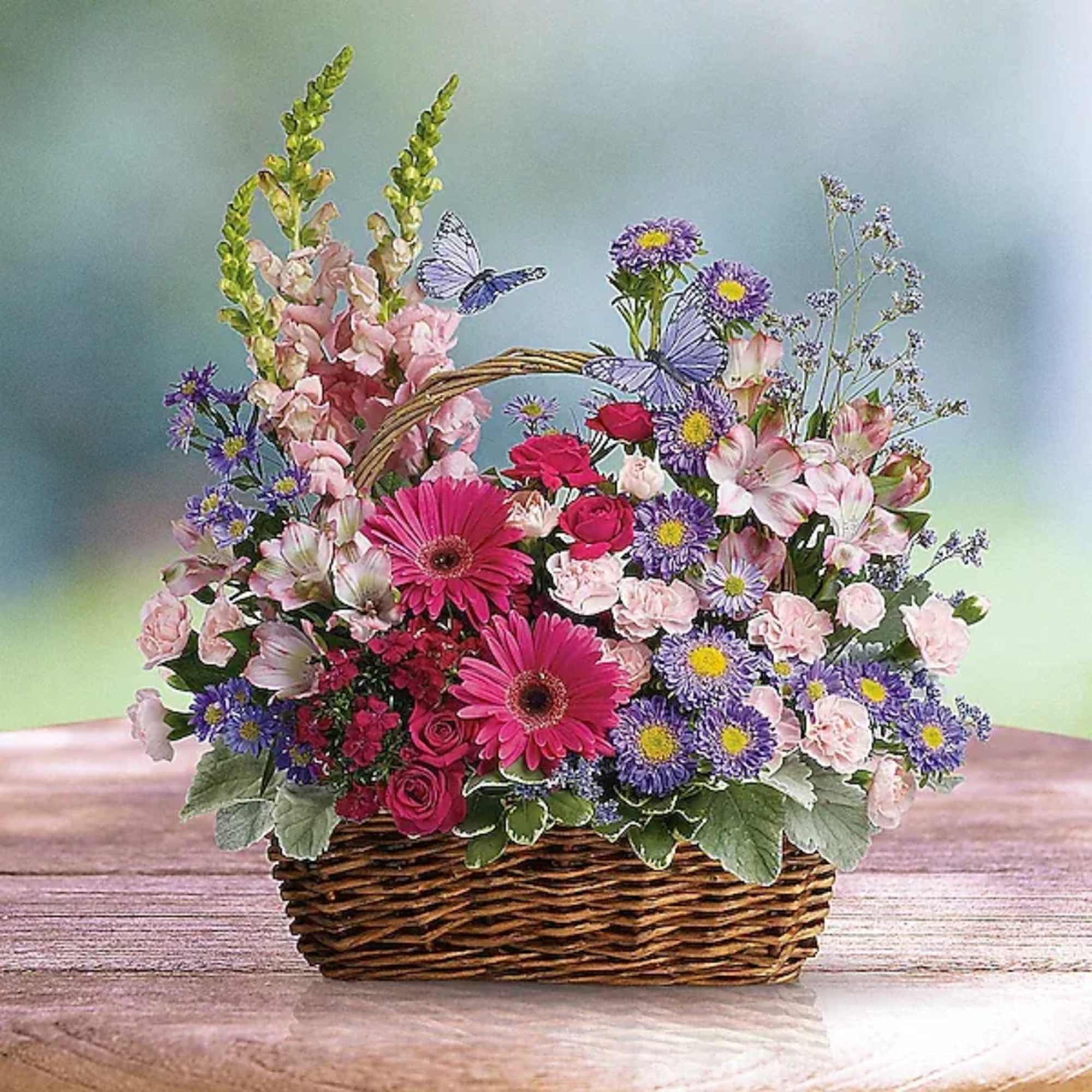 Mixed bouquet in a wicker basket with pink, purple, and white flowers