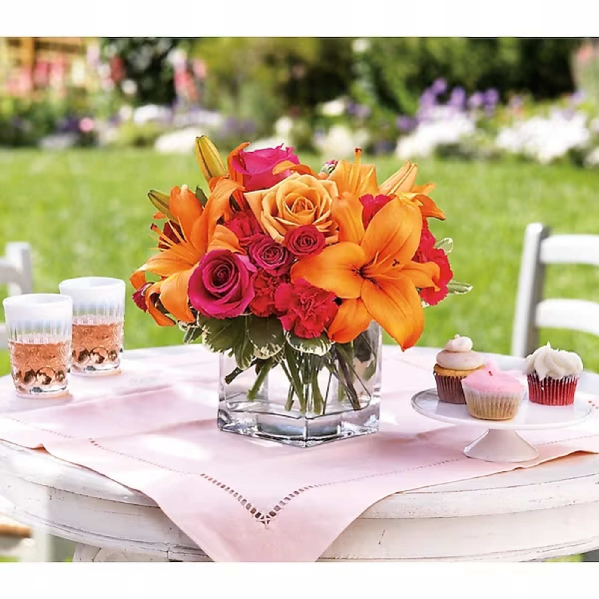 Bouquet of orange lilies and pink roses in a glass vase on a table