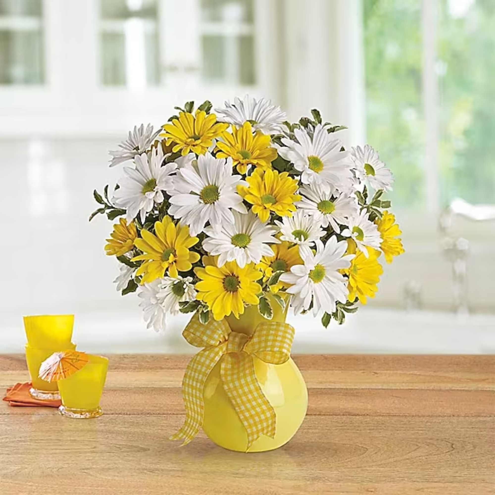 Yellow and white daisy bouquet in a yellow vase with a ribbon