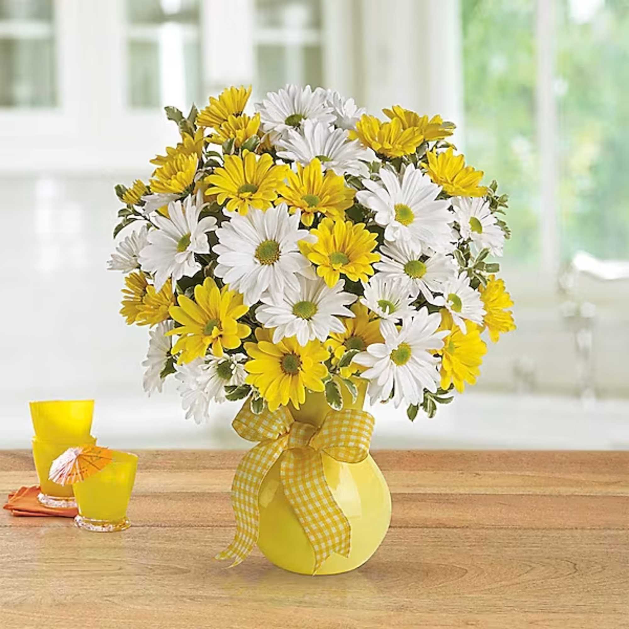 Yellow and white daisy bouquet in a yellow vase with a gingham ribbon