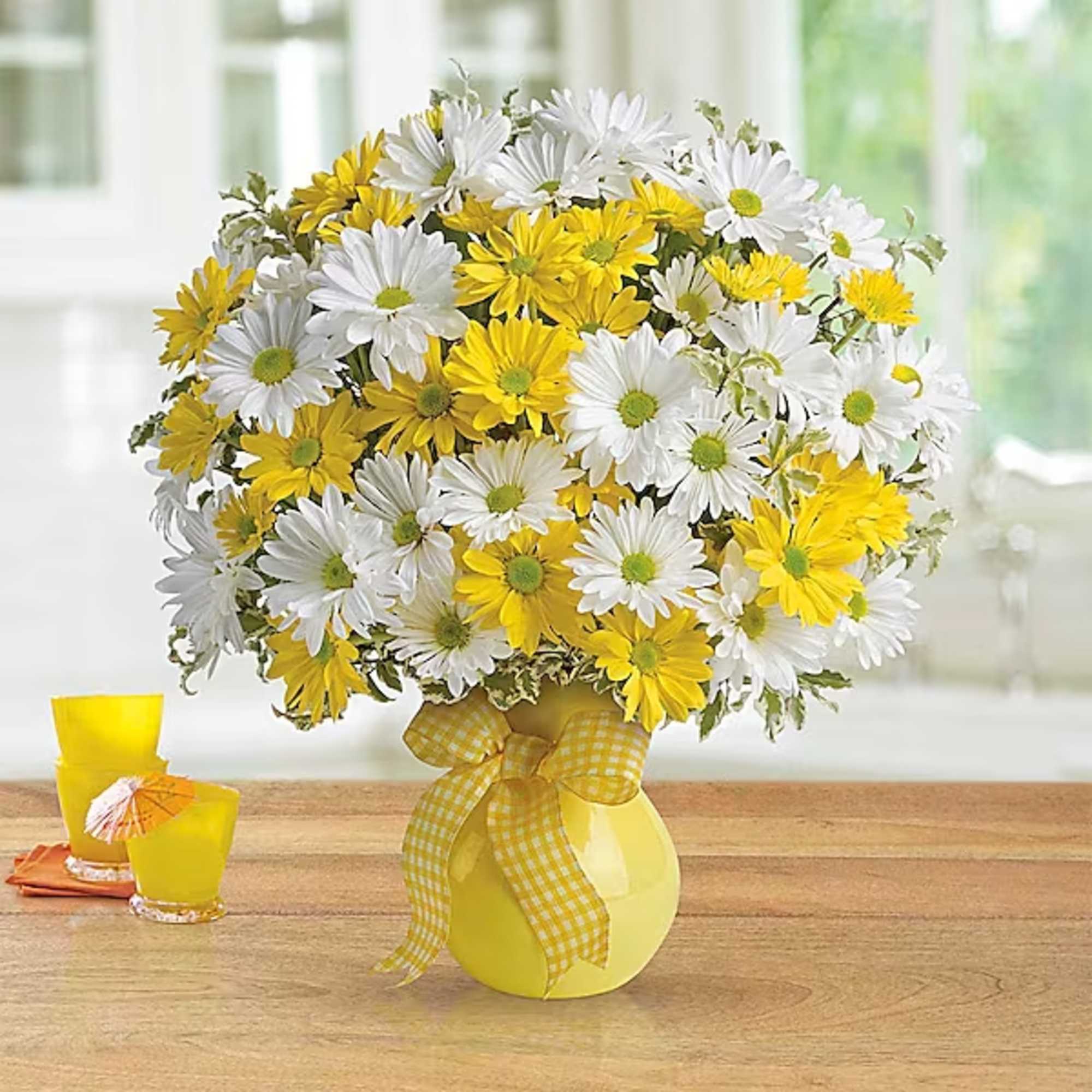 Yellow and white daisy bouquet in a yellow vase with a ribbon