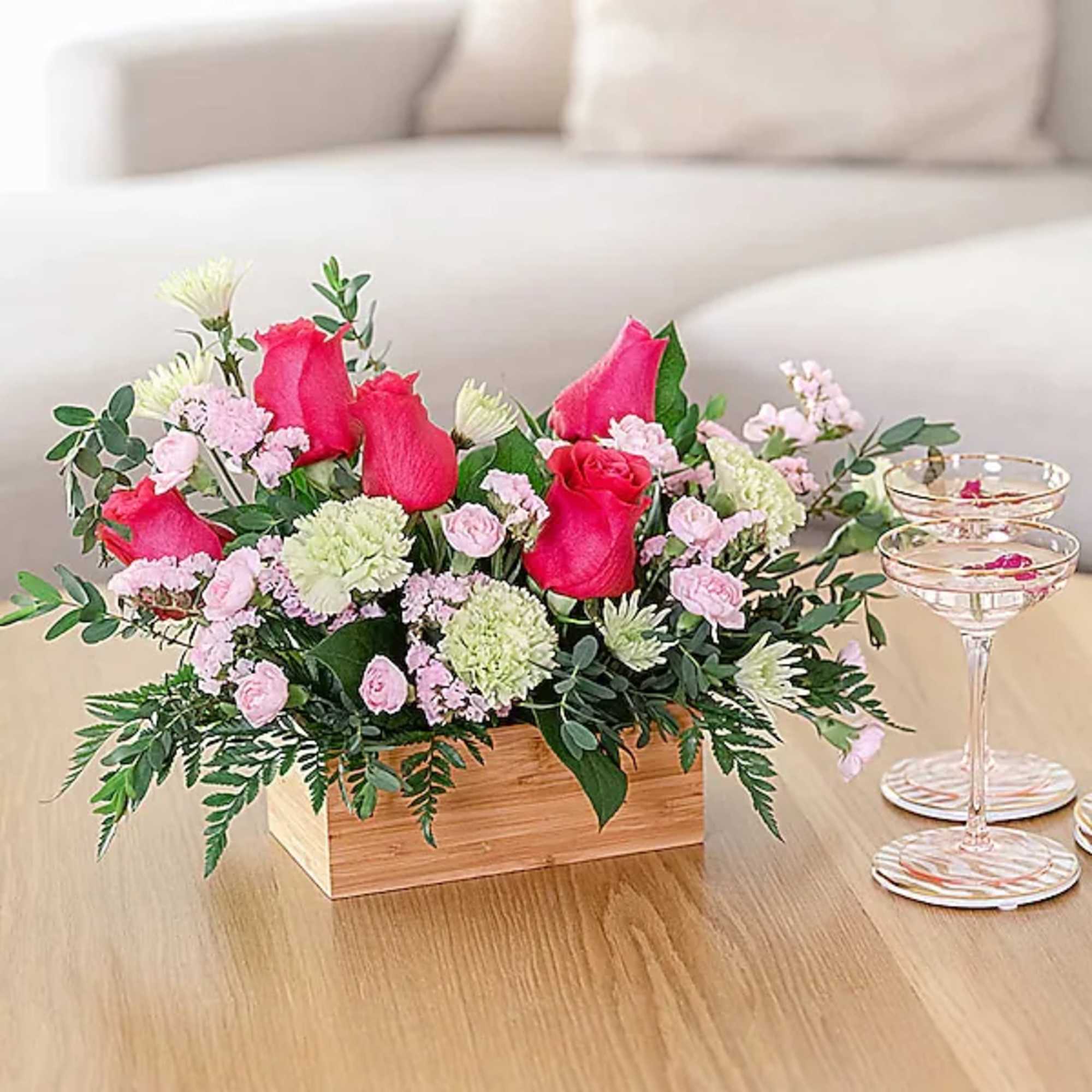 Pink rose arrangement in a wooden box with small pastel flowers