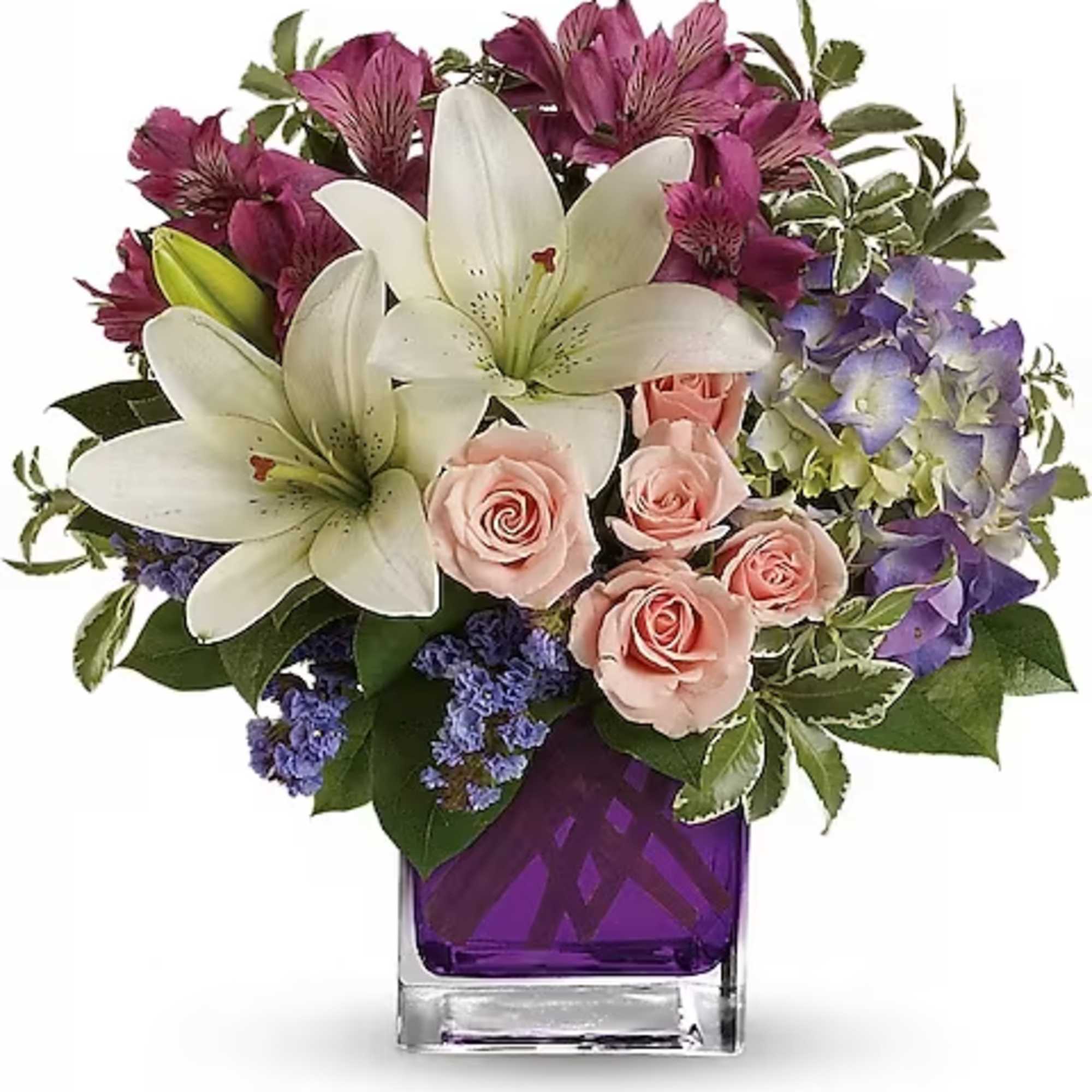Bouquet of white lilies, pink roses, and purple flowers in a purple glass vase