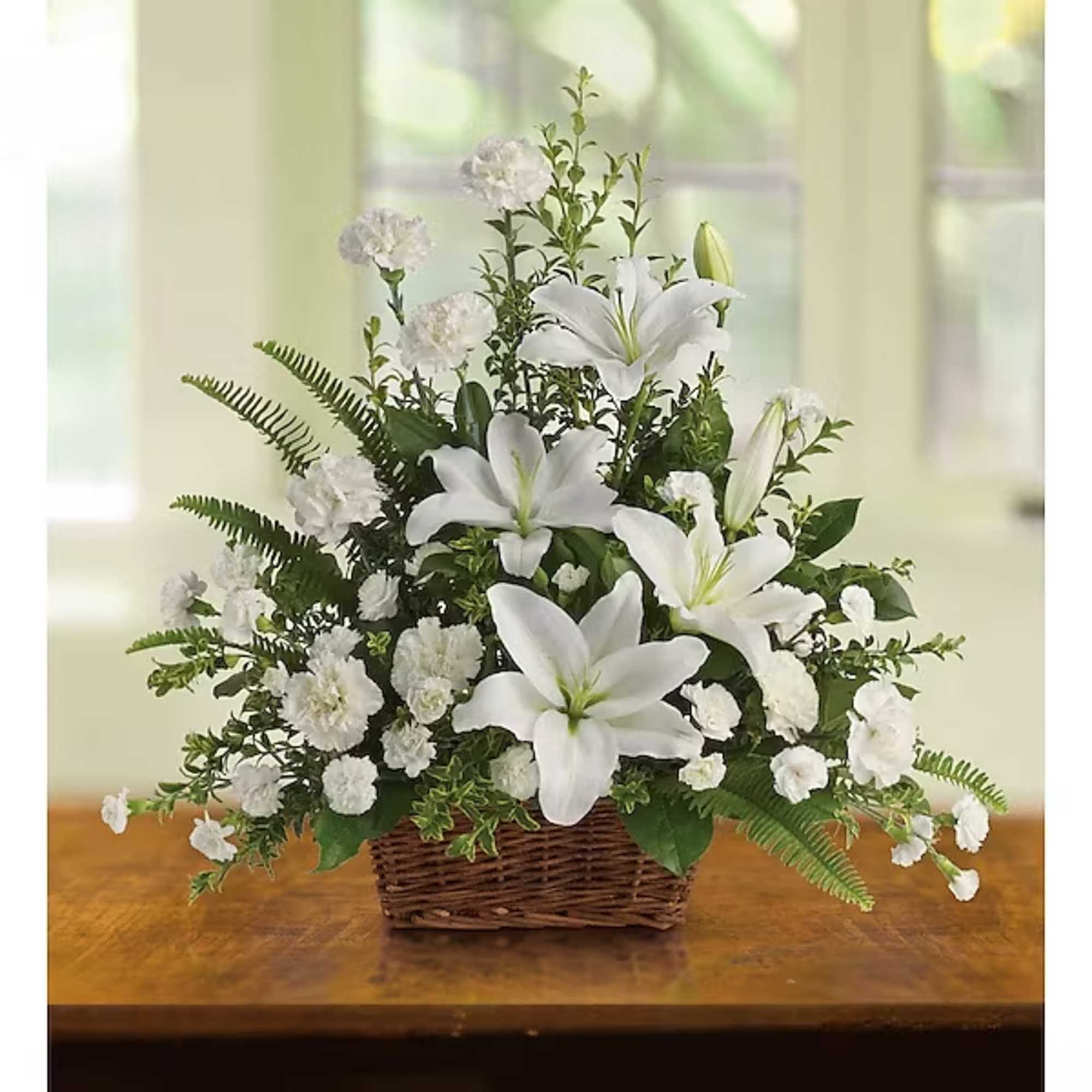 White lilies and carnations arranged in a wicker basket