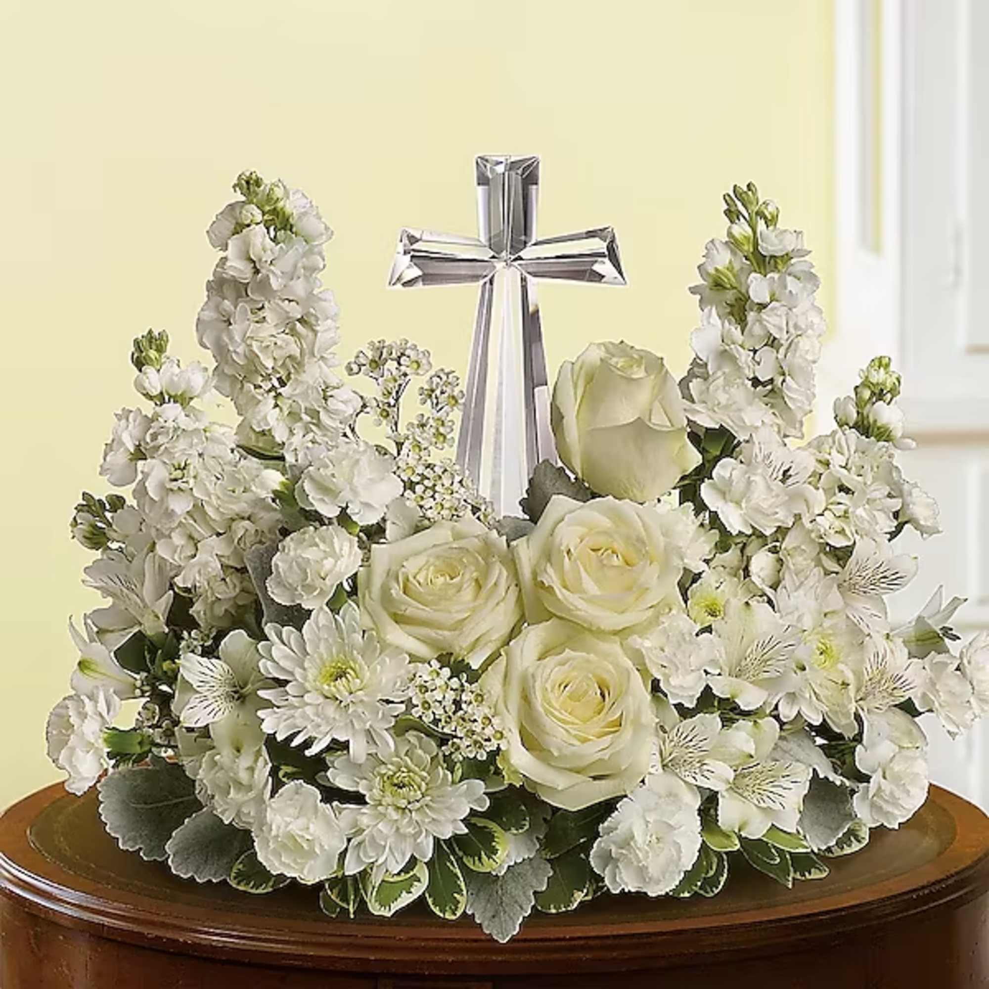 White floral arrangement with roses and a silver cross centerpiece