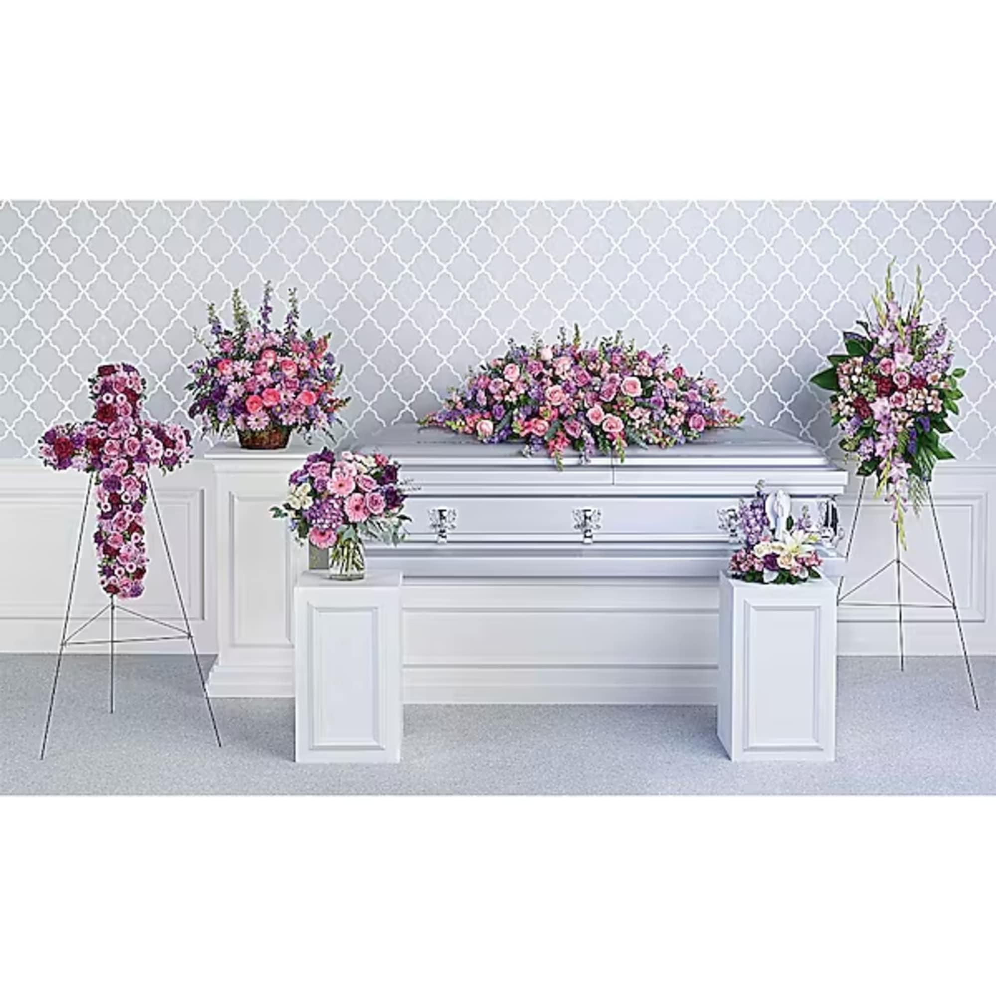 Floral funeral display with pink and purple arrangements around a white casket