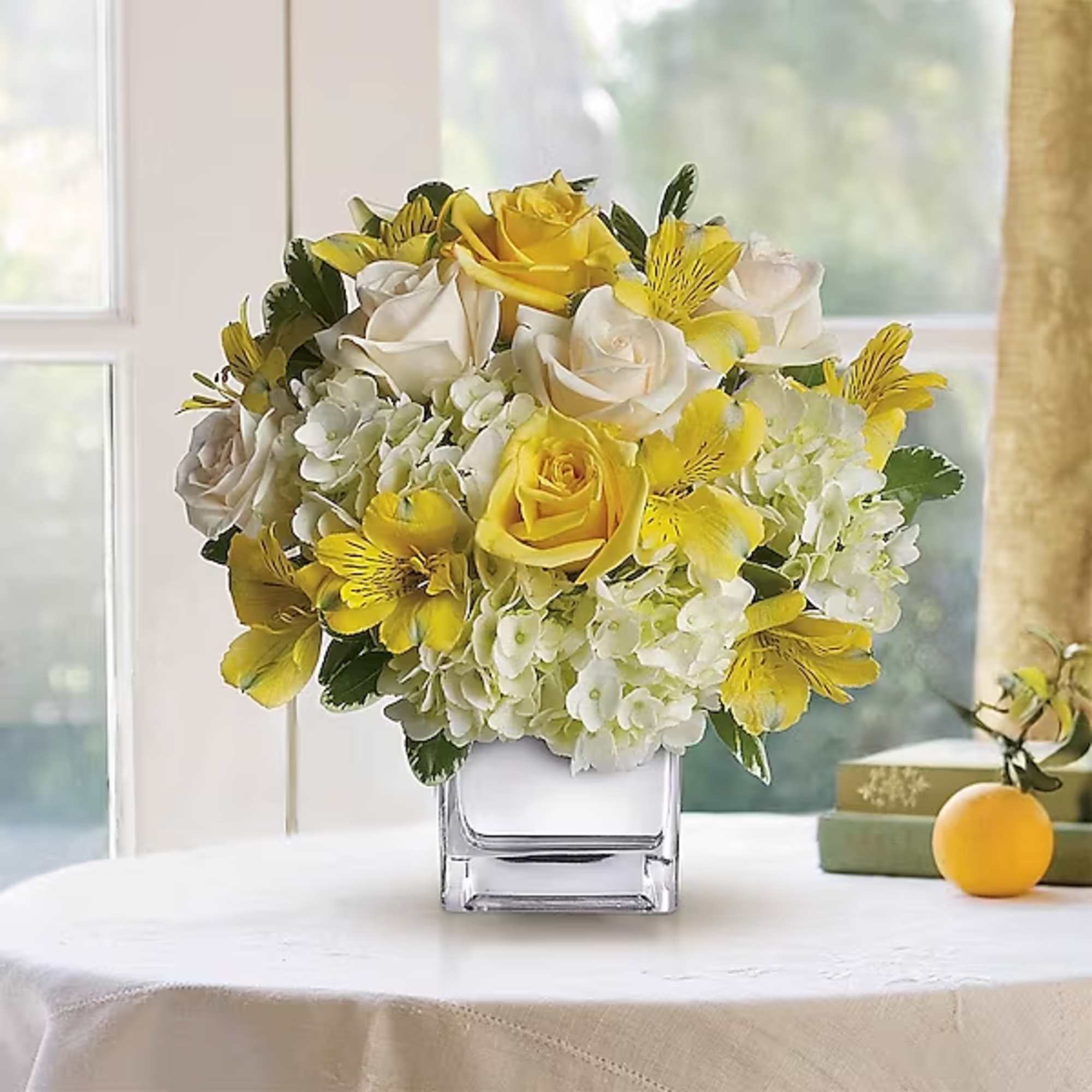Yellow and white flower arrangement in a square glass vase