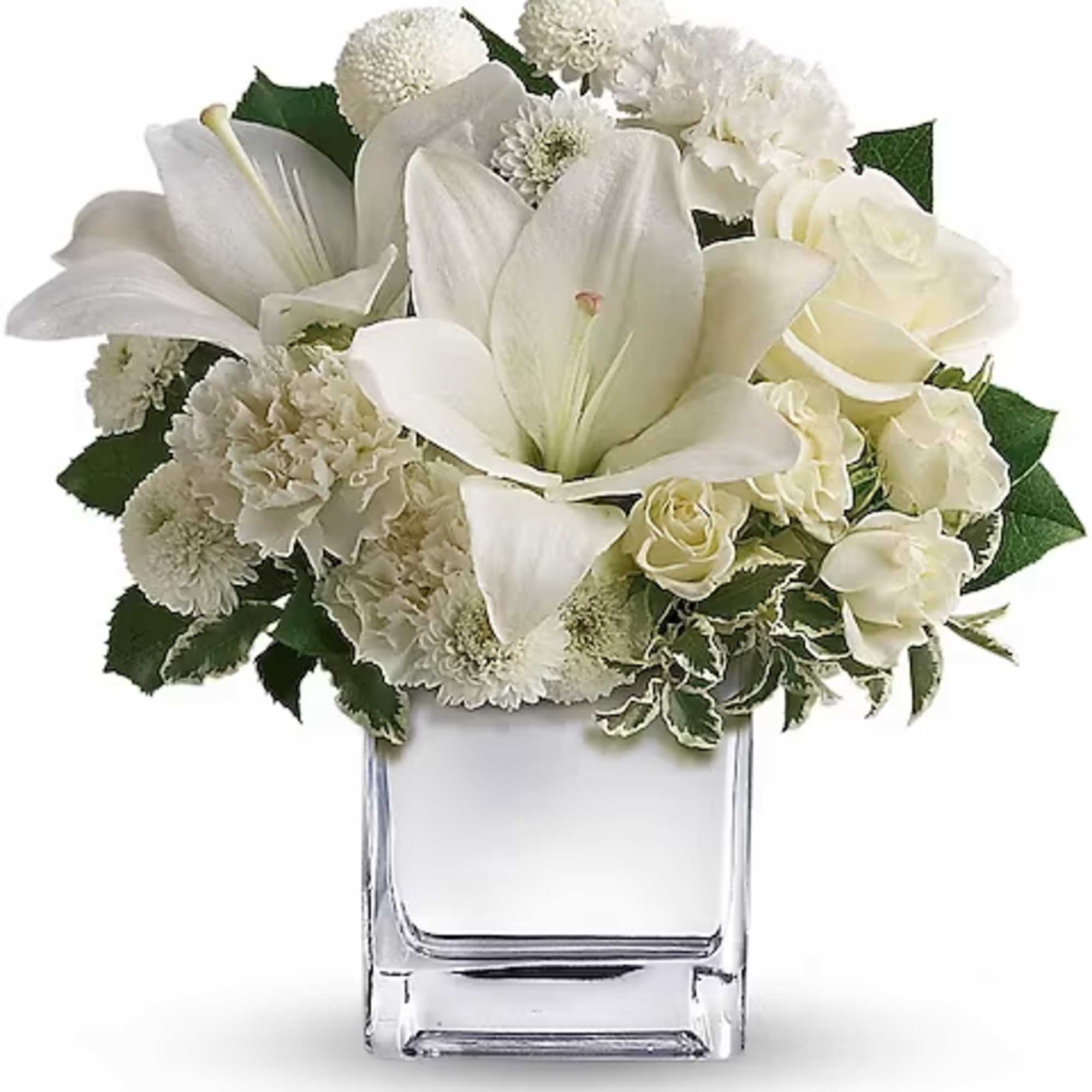 White lilies and roses arranged in a clear square vase