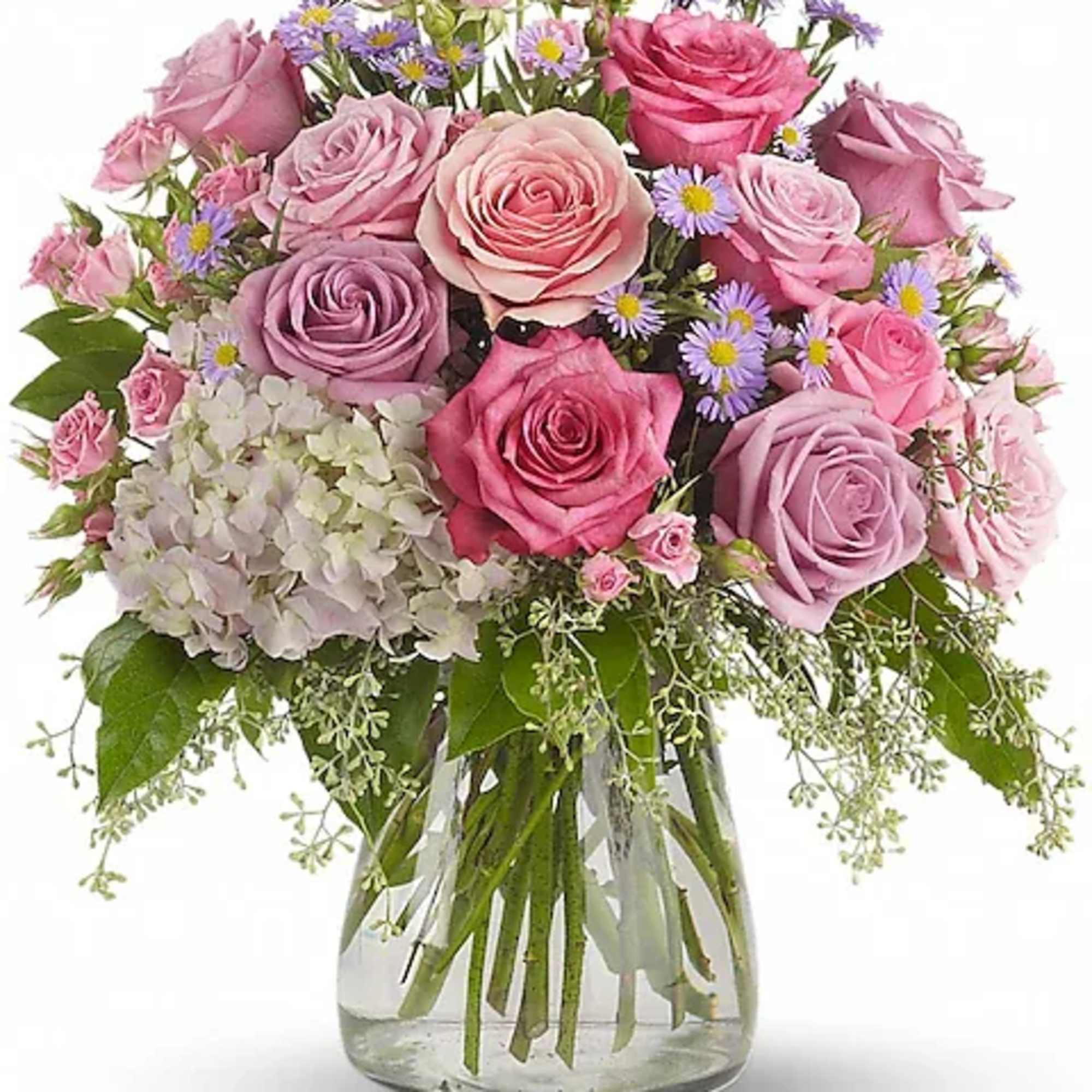 Pink and lavender roses in a clear glass vase with small purple daisies