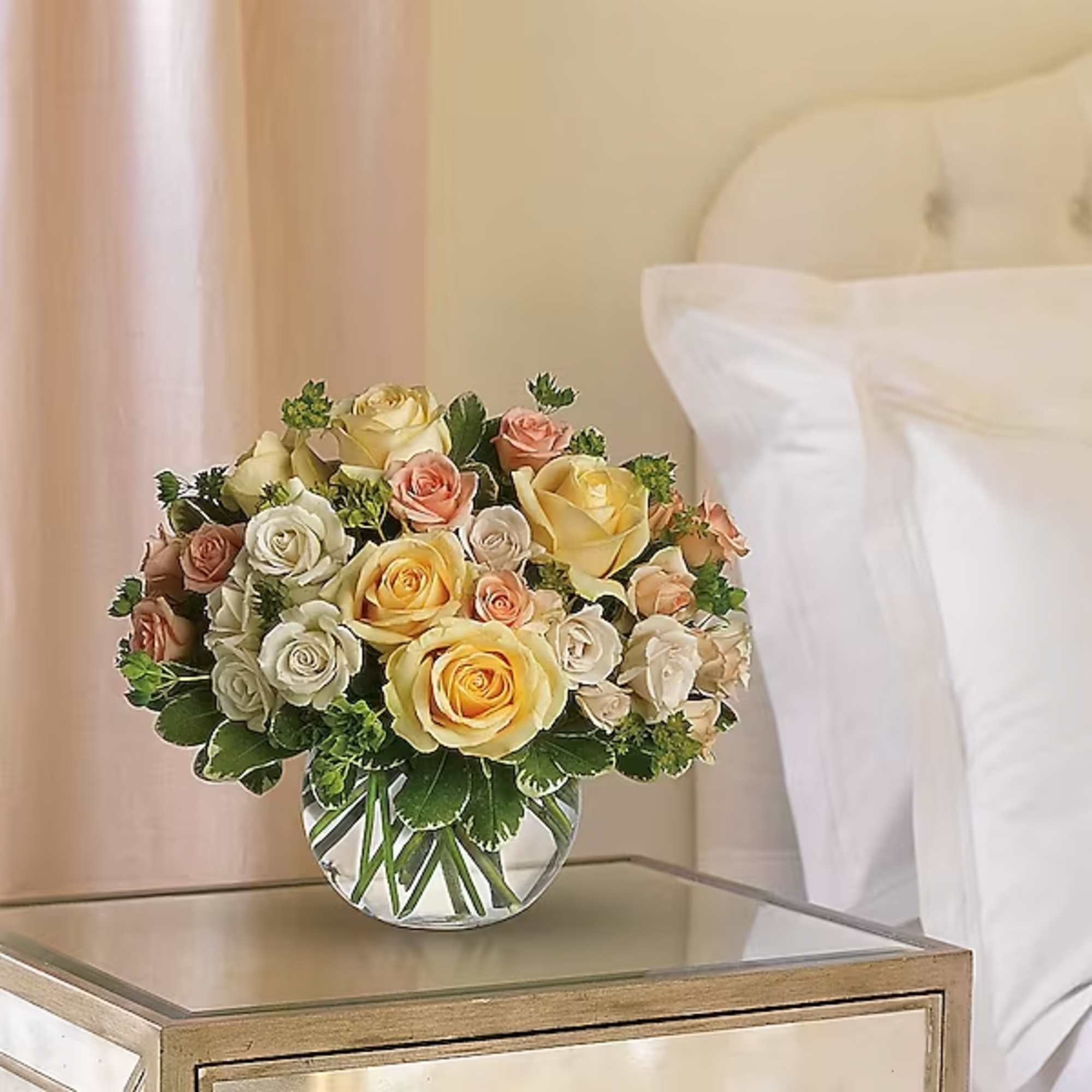 Bouquet of cream, yellow, and peach roses in a clear glass vase