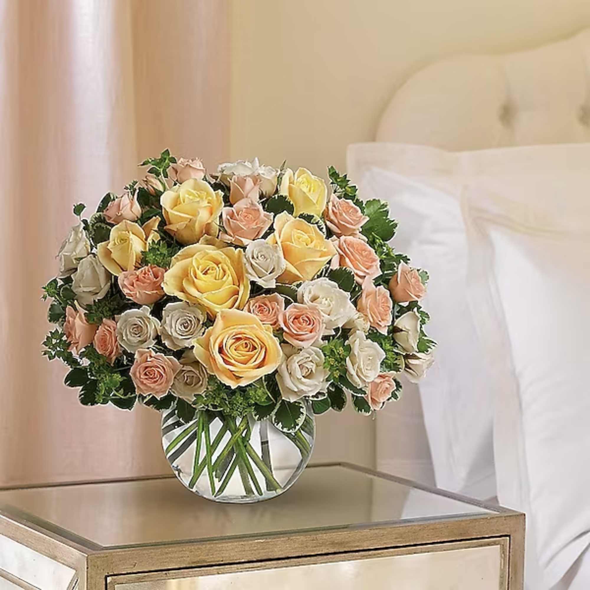 Bouquet of yellow, peach, and white roses in a clear glass vase