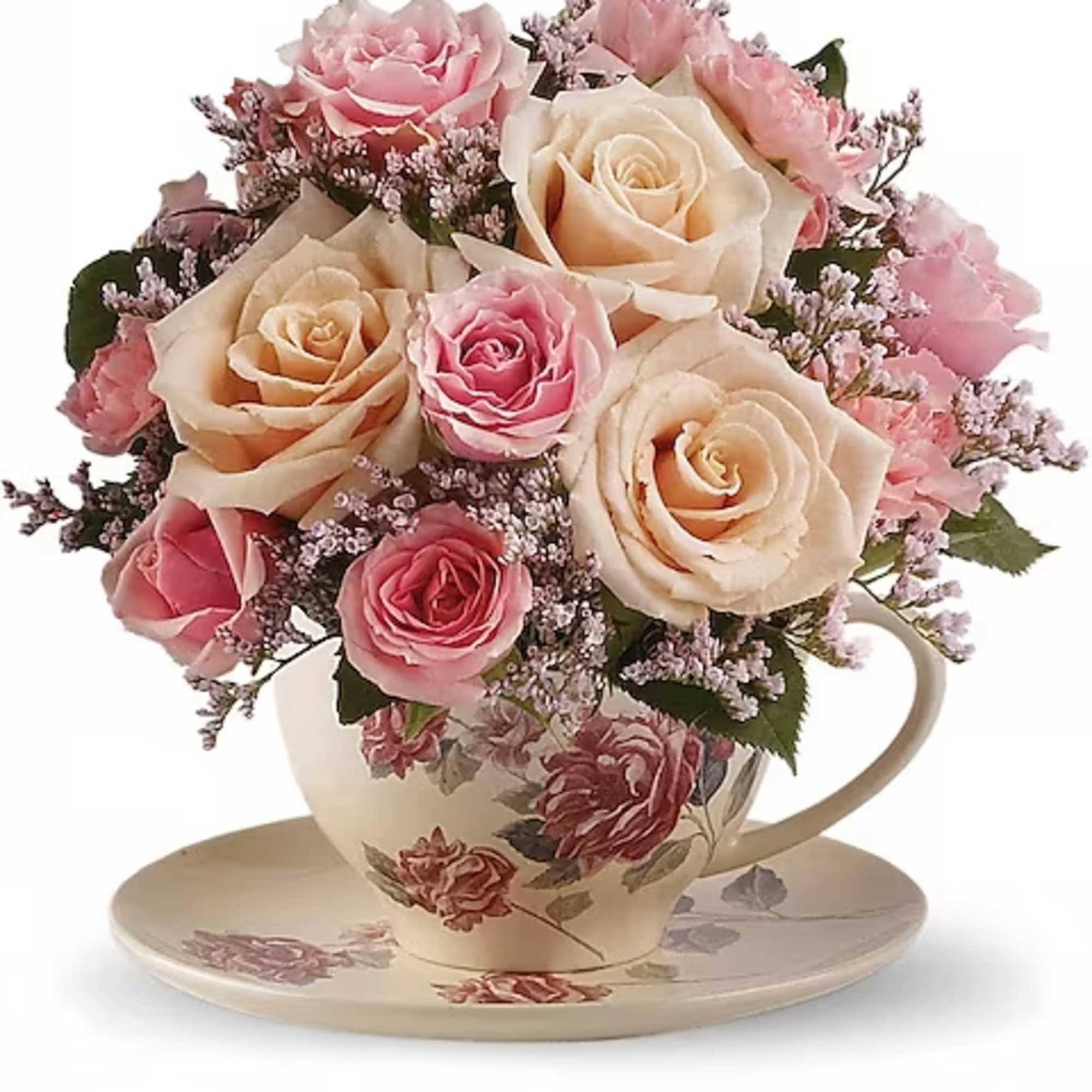 Pink and cream roses arranged in a floral teacup with saucer