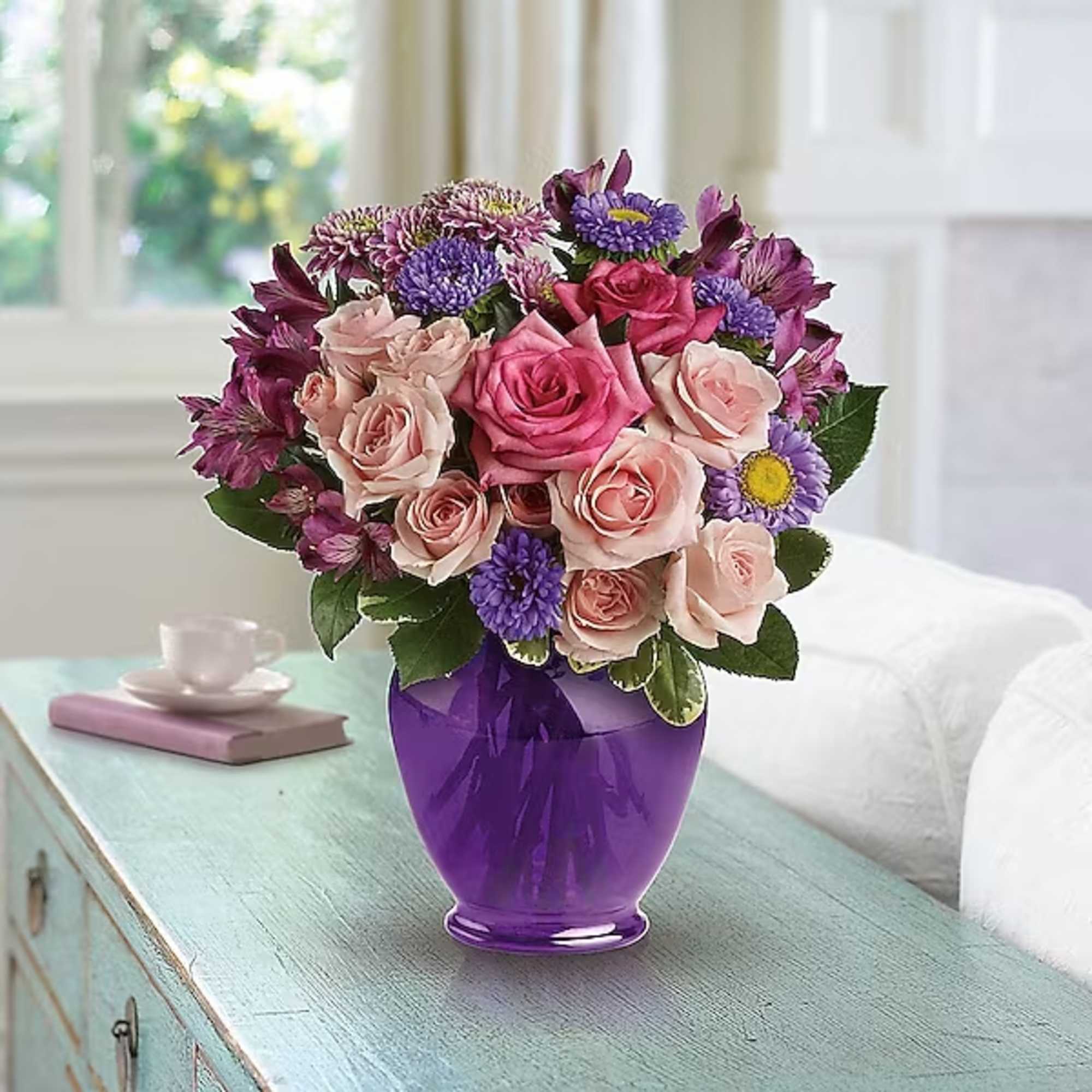 Pink and purple mixed flower bouquet in a purple vase