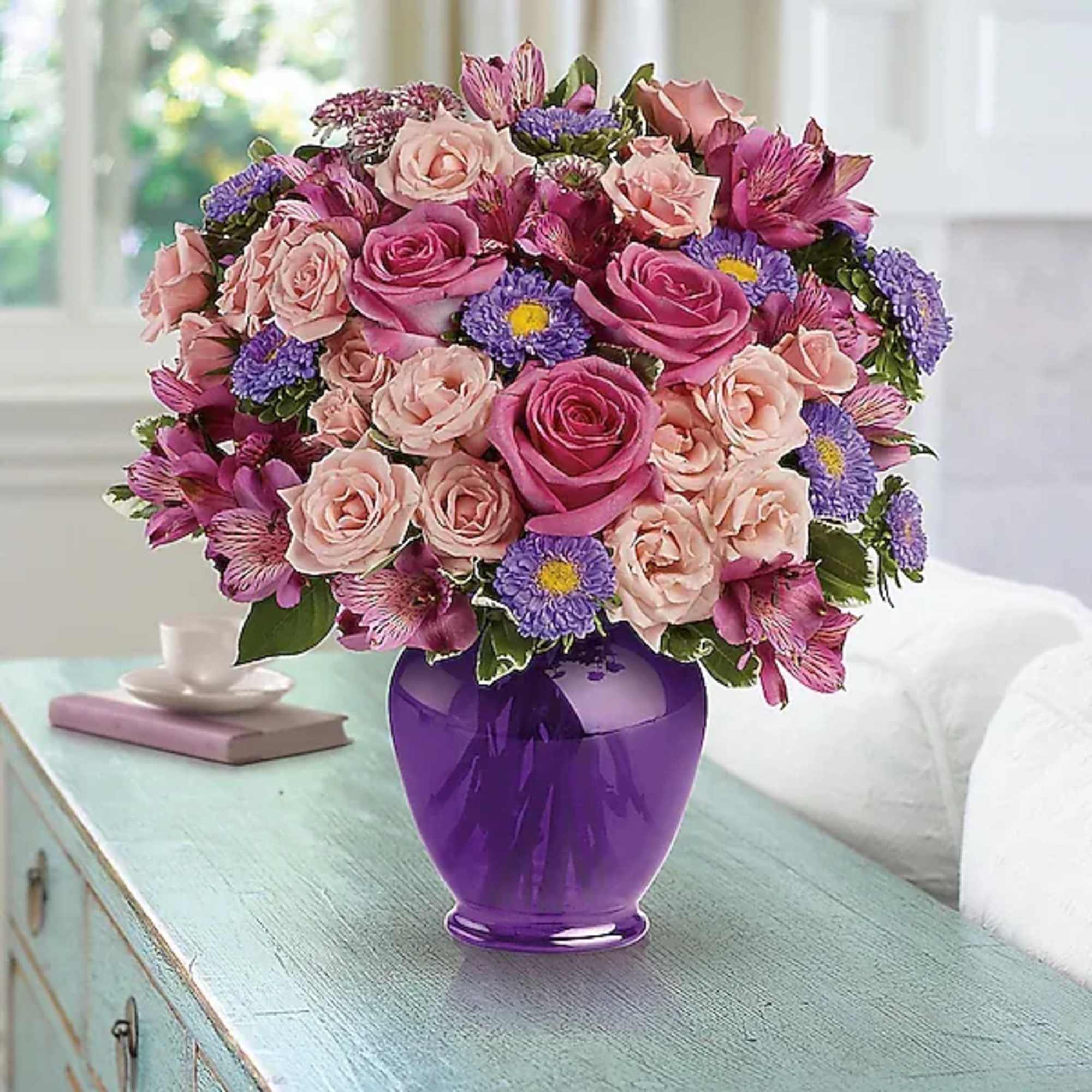 Pink and purple mixed flower bouquet in a purple vase