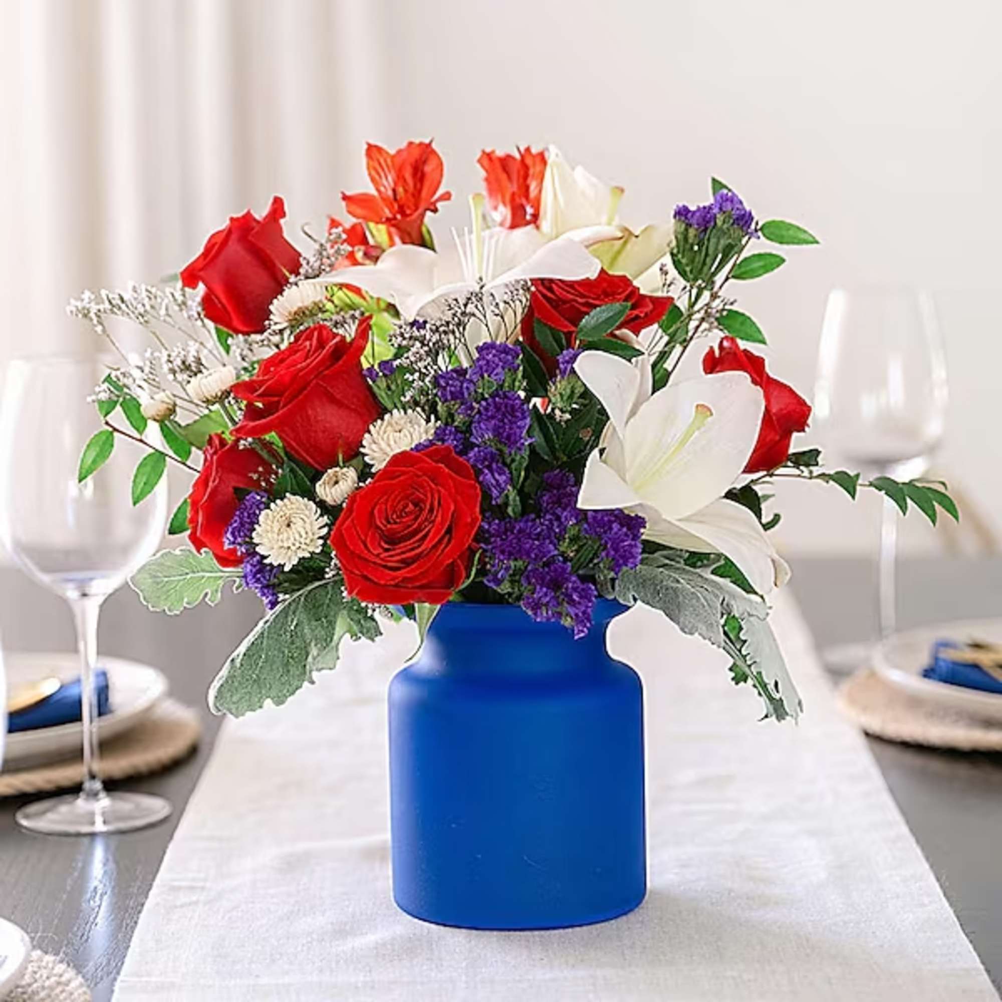 Red roses and white lilies in a blue vase on a table