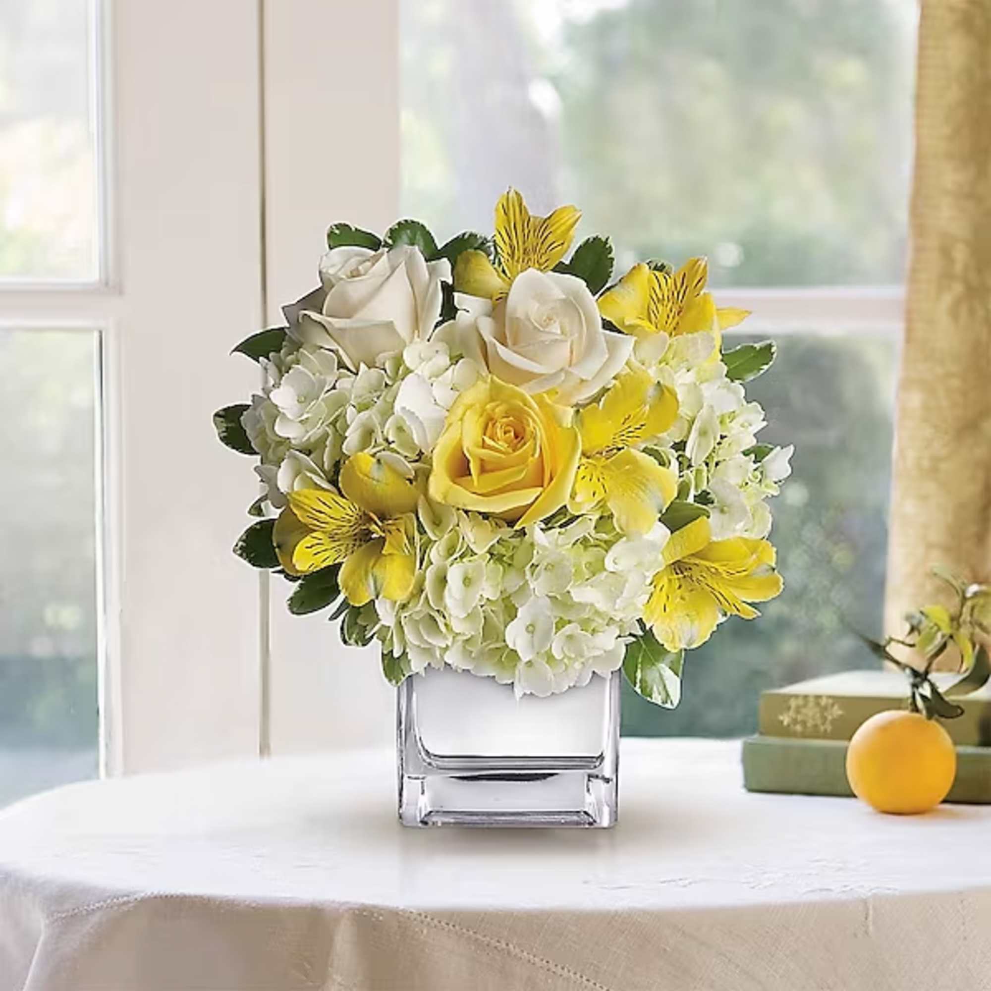 Yellow and white floral arrangement in a square glass vase