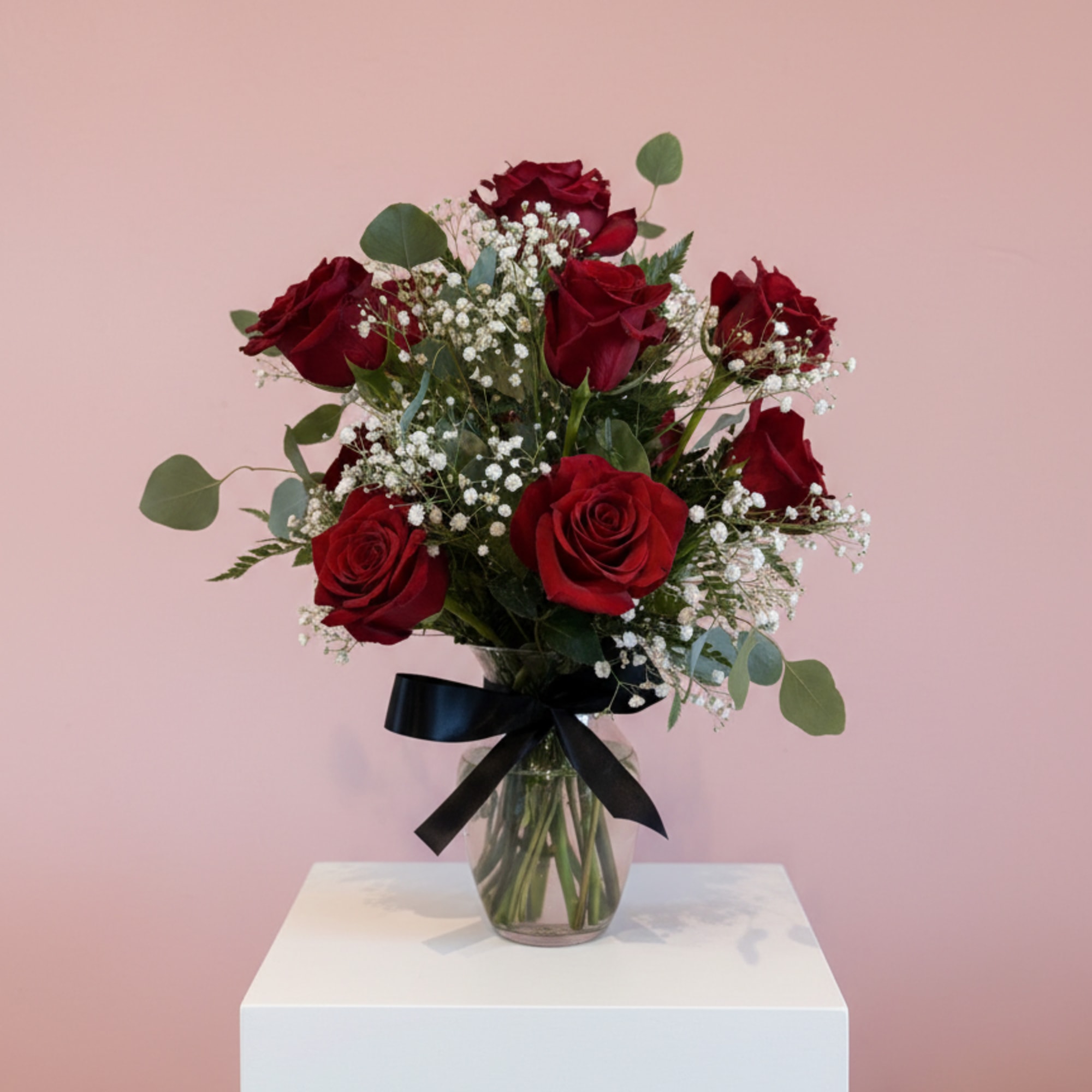 Bouquet of red roses in a glass vase with a black ribbon