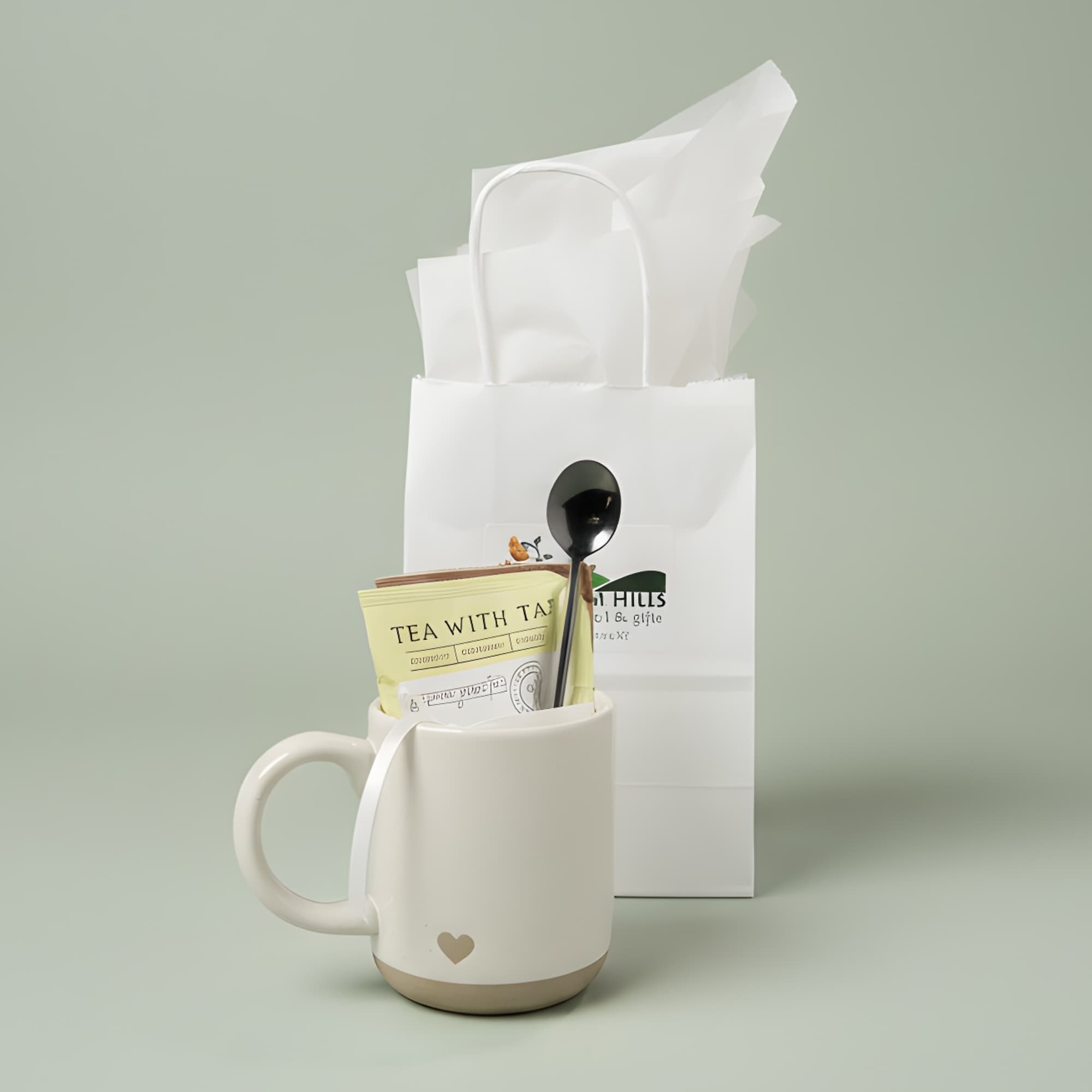 White mug gift set with tea packet and spoon in a paper bag